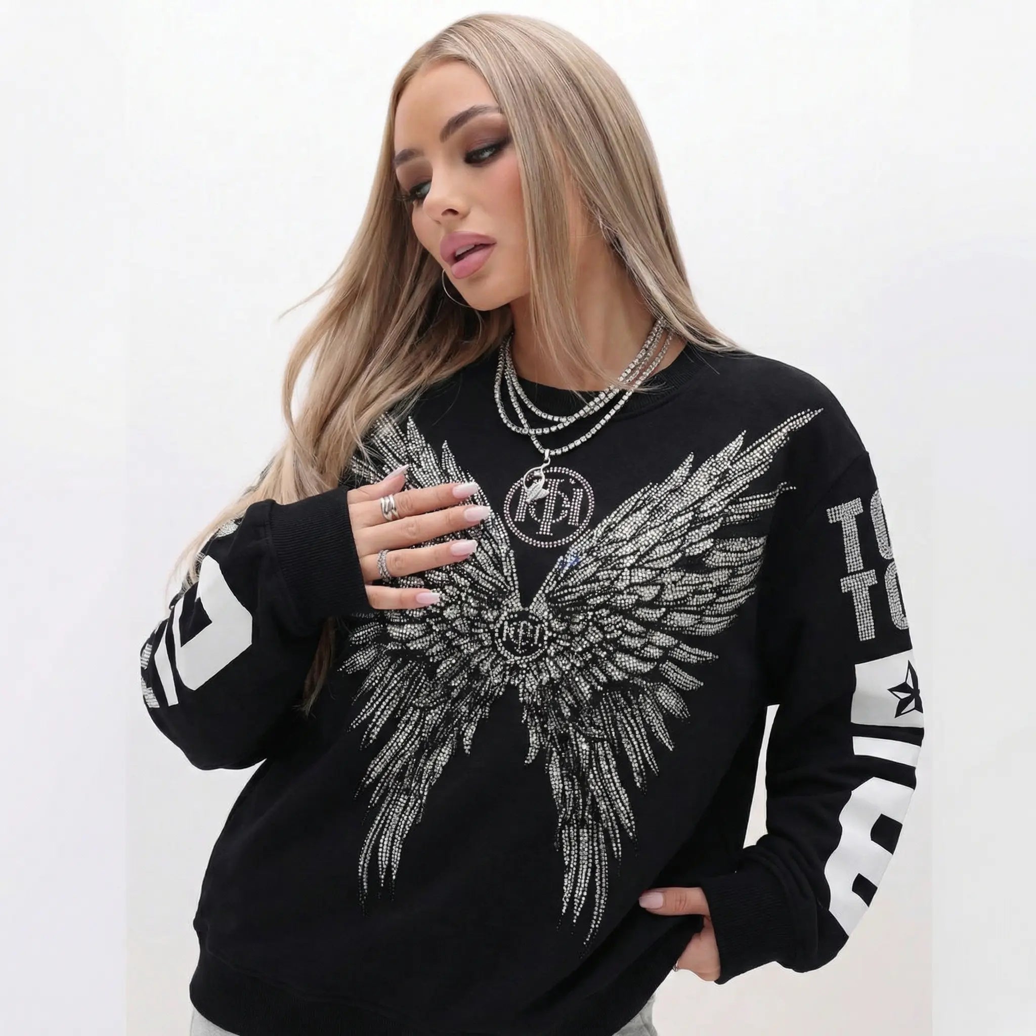 Woman wearing a black sweatshirt with silver wing design and branding on a white background, TCH 1976 Rhinestone Wings Sweatshirt