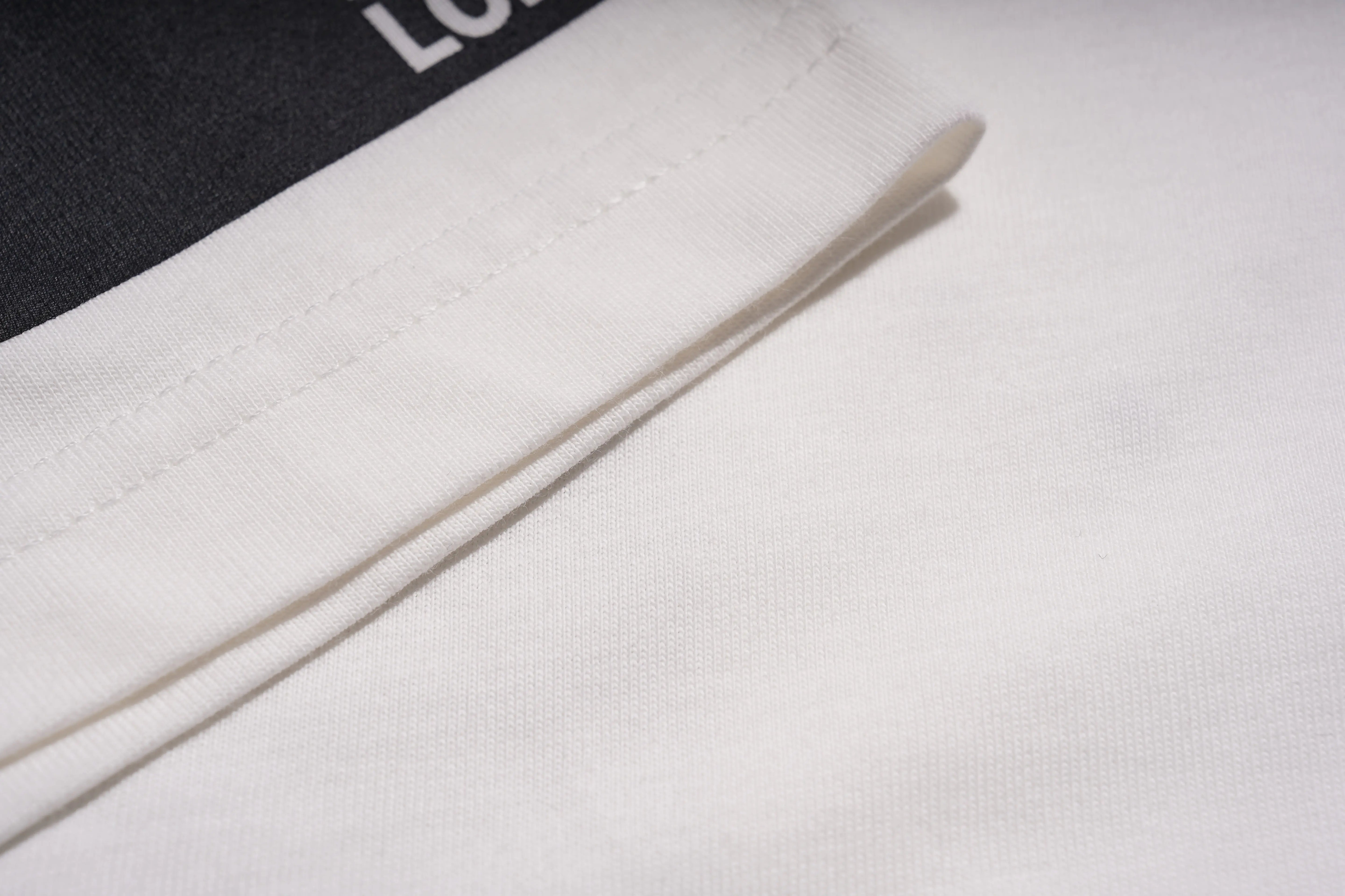 Close-up of a white cylindrical object on a textured surface with 'LOVE' branding. TCH Anarchy Graphic Rhinestone T-Shirt