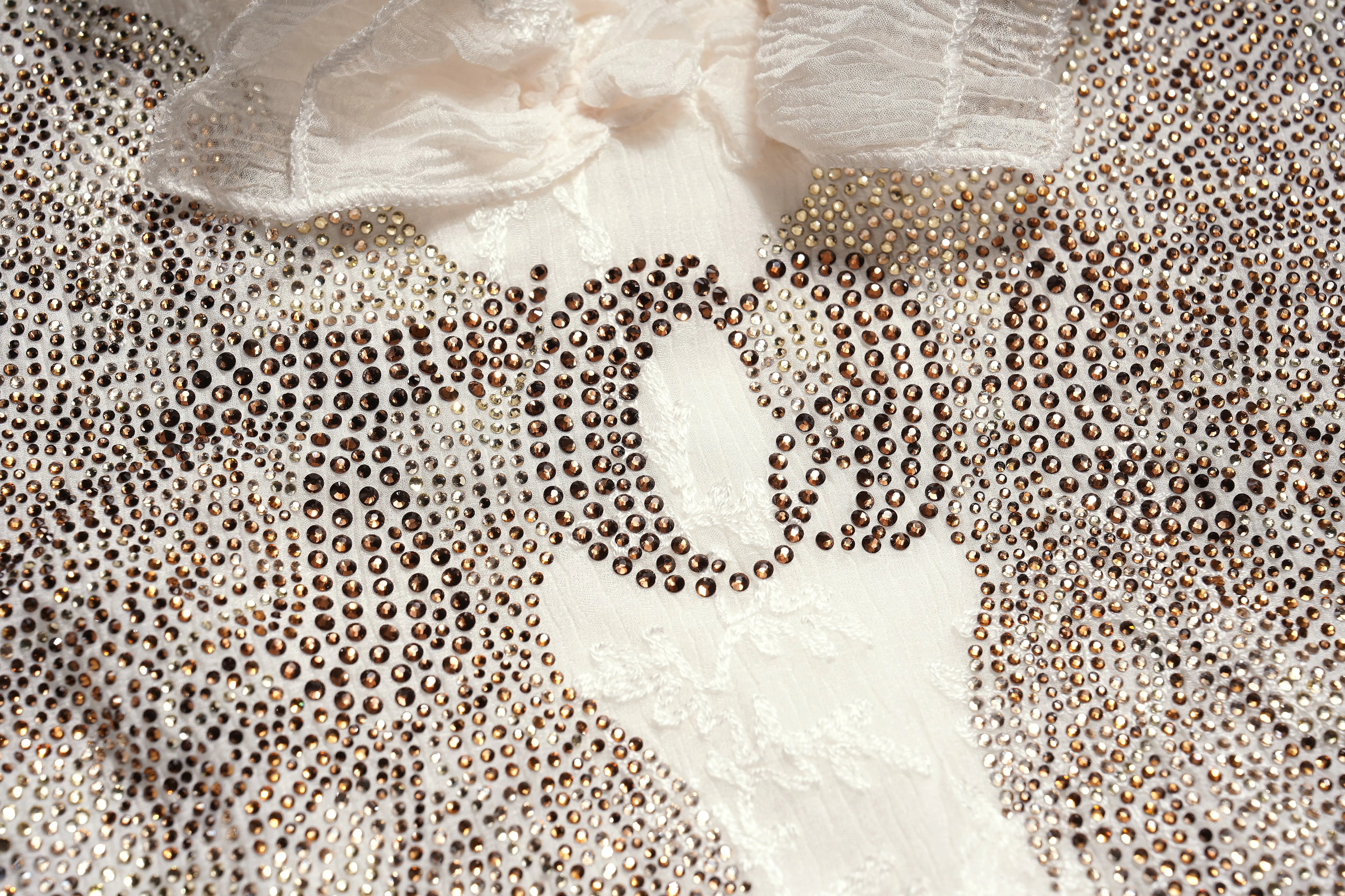 Close-up of a textured fabric with small beads or stones. TCH Angel Wings Rhinestone Ruffle Blouse