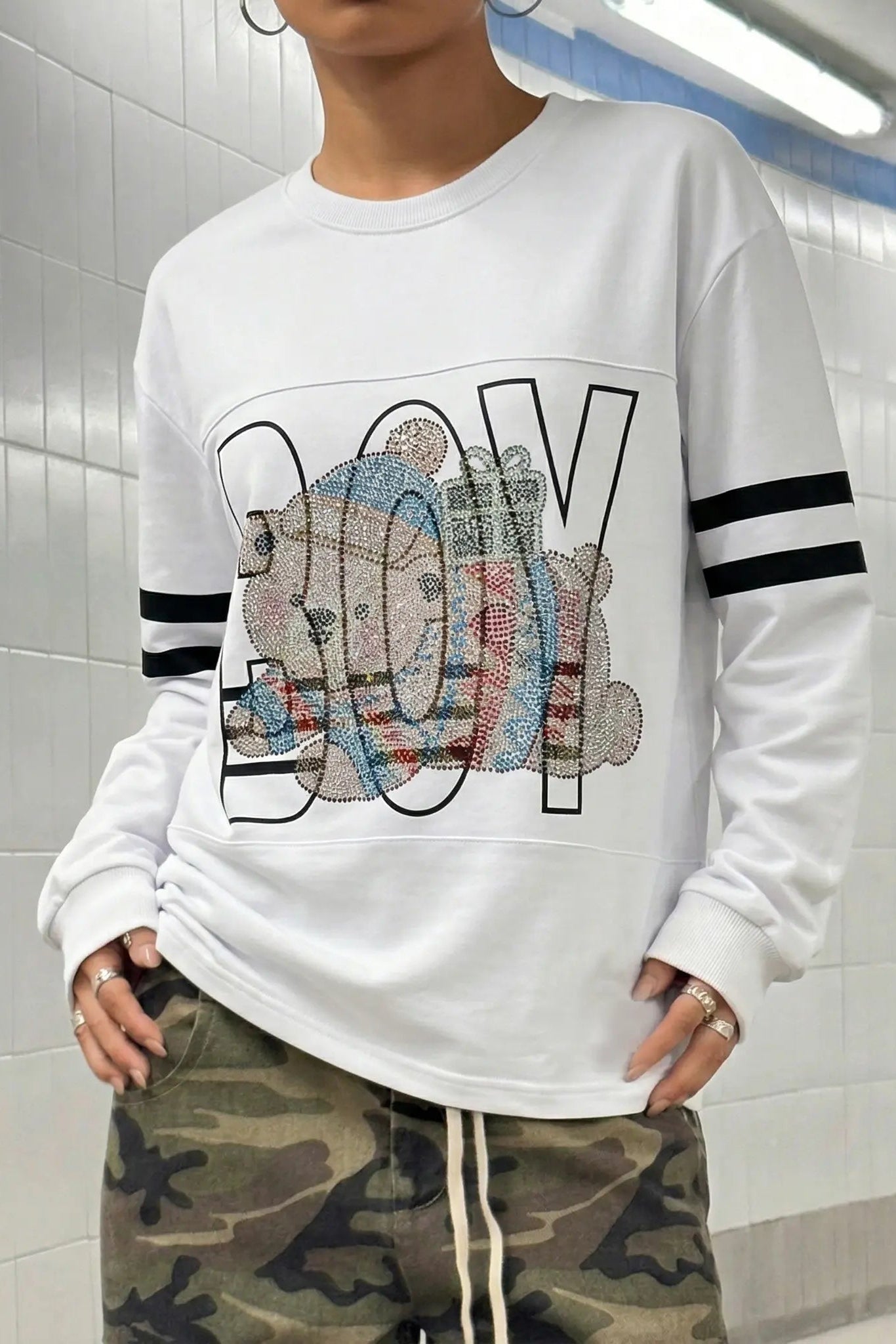 Person wearing a white sweatshirt with colorful text design in an indoor setting TCH BOY Rhinestone Bear Sweatshirt-