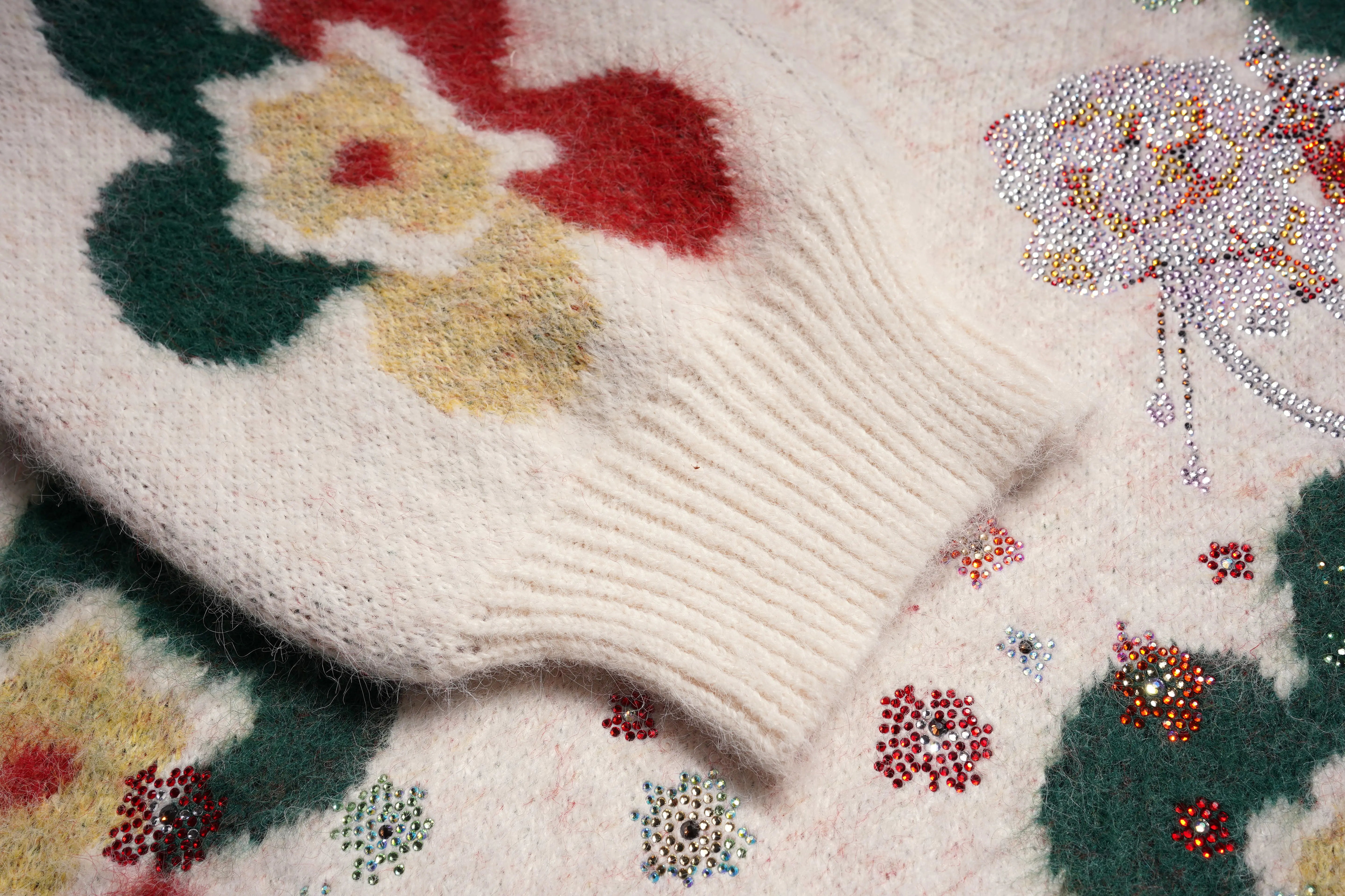 Close-up of a knitted fabric with floral patterns and colorful beads. TCH Beige Floral Rhinestone V-Neck Sweater & Wool Mini Skirt Set