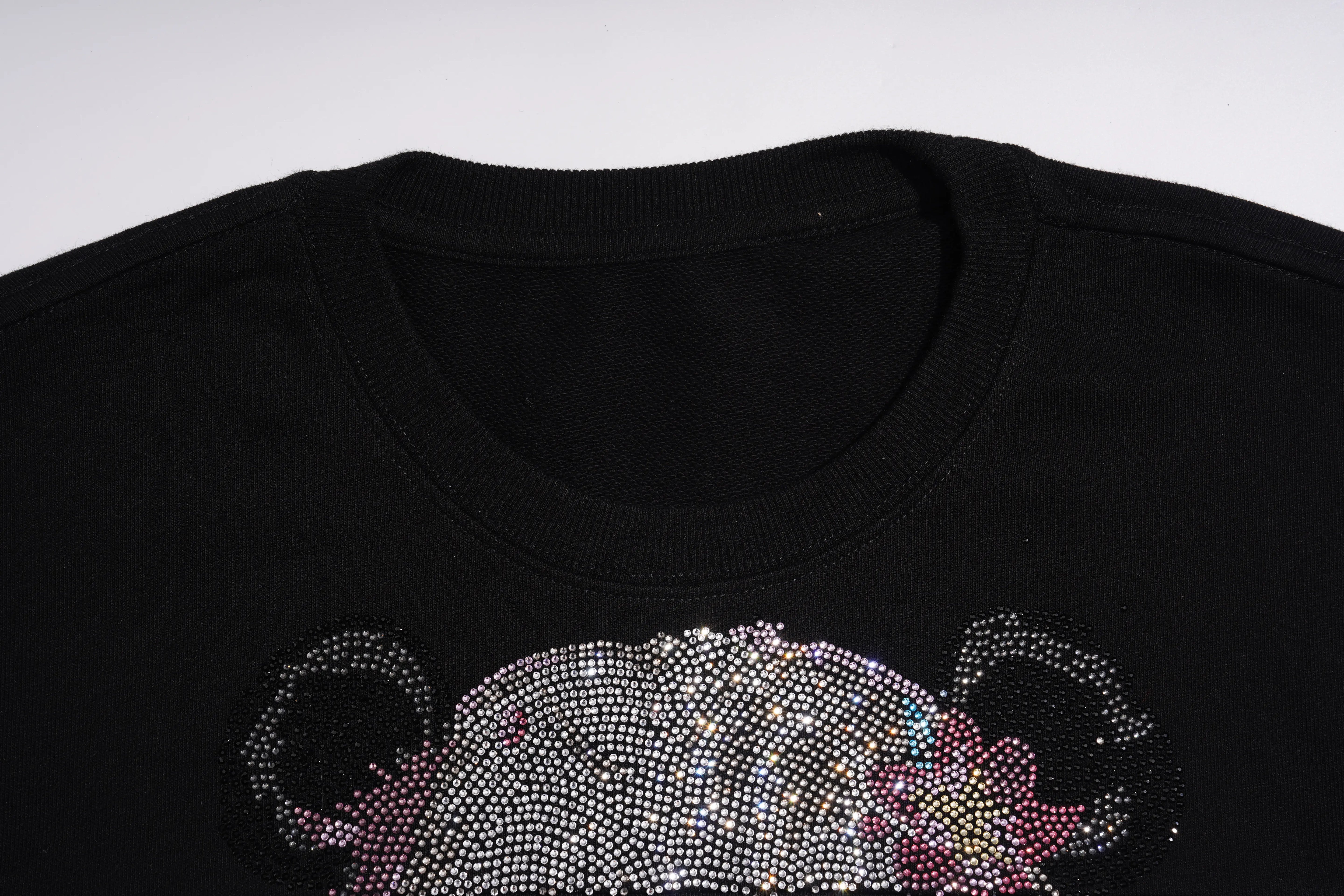 Close-up of a black crewneck sweatshirt featuring a large, sparkling rhinestone graphic of a bear face on the front. TCH Black Panda Rhinestone Sweatshirt