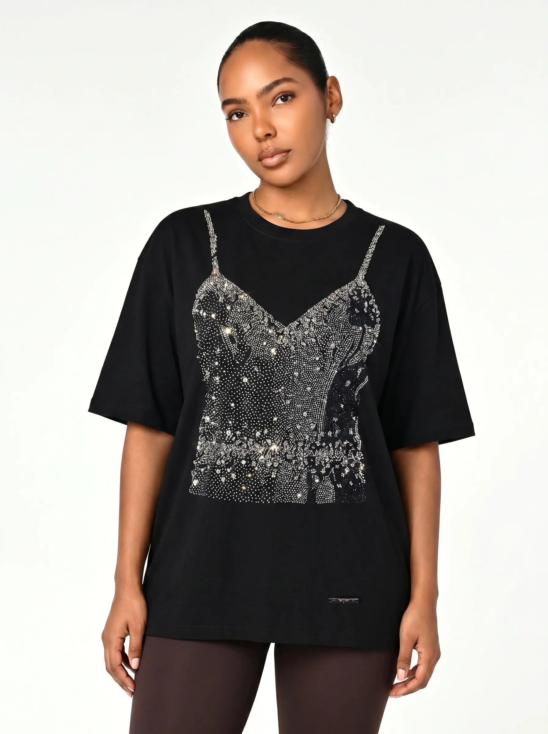 A woman modeling a black oversized t-shirt featuring a large rhinestone-embellished camisole graphic on the front, set against a plain white studio background. TCH Black Rhinestone Corset Graphic T-Shirt