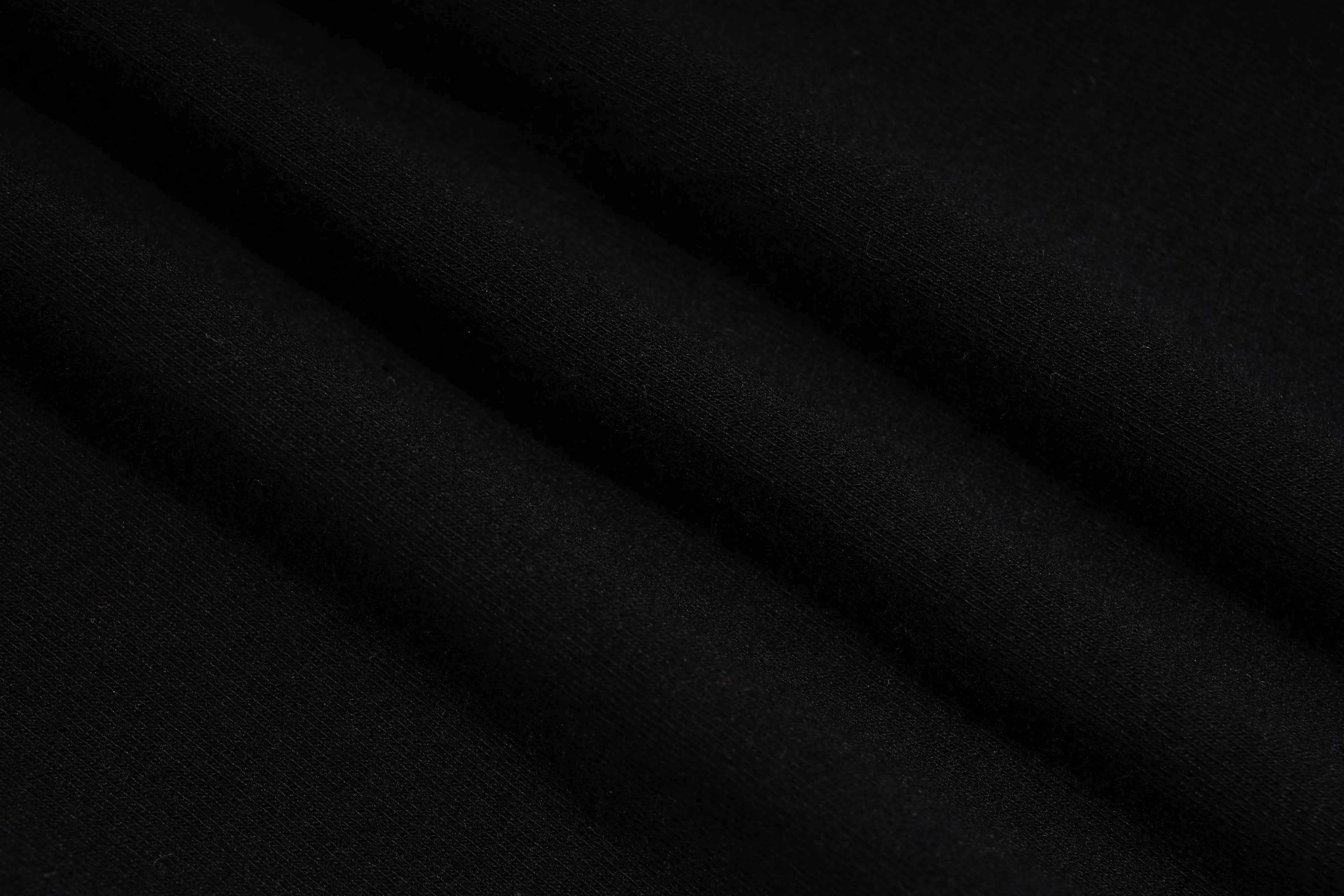 A close-up of draped black fabric with soft diagonal folds showing a fine knit texture. TCH Black Rhinestone Floral Leggings