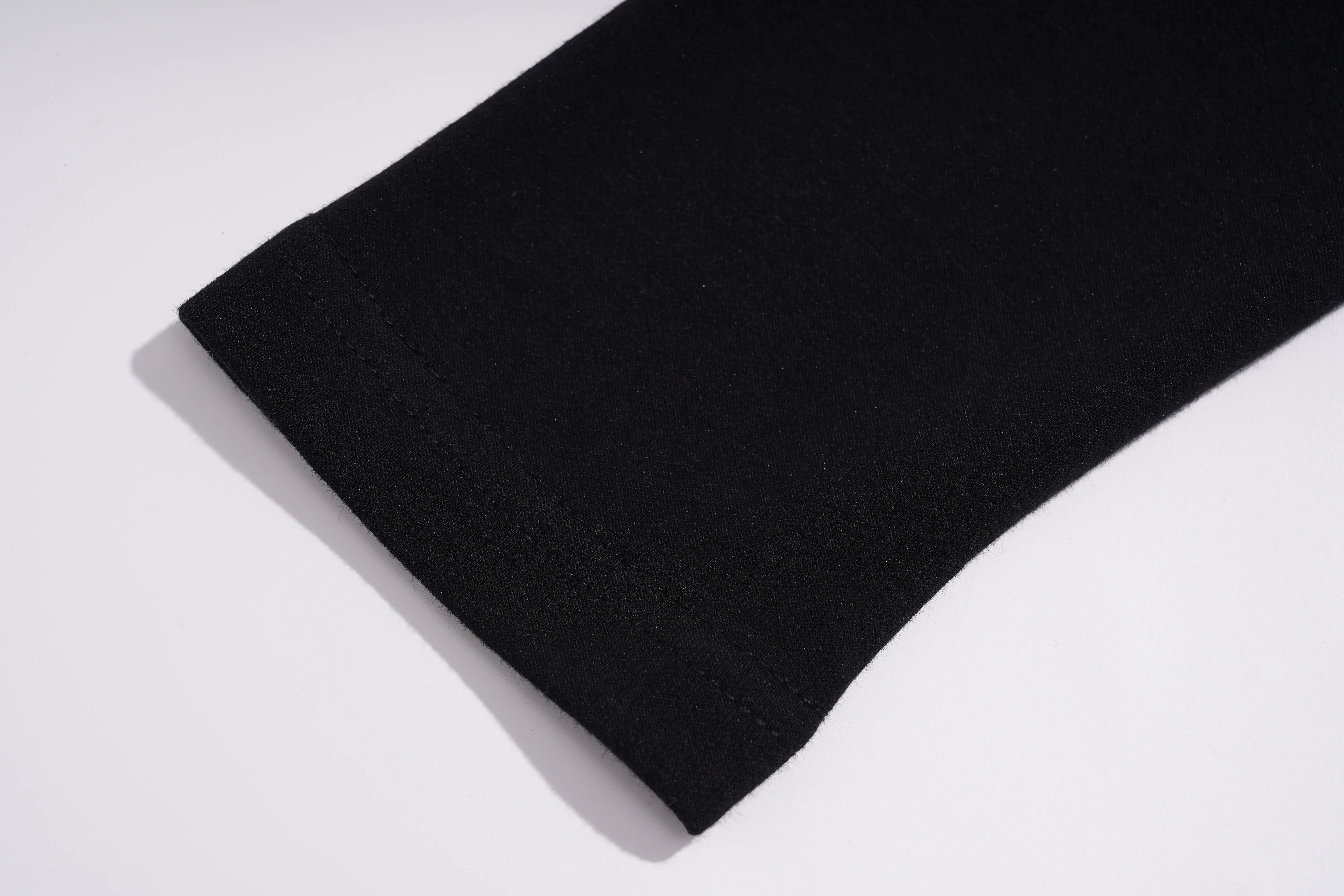 A close-up of a black knit fabric cuff, likely from a sweater or long-sleeve garment, showing the texture and hem stitching on a clean white background. TCH Black Rhinestone Fringe Detail Long Sleeve Mini Dress
