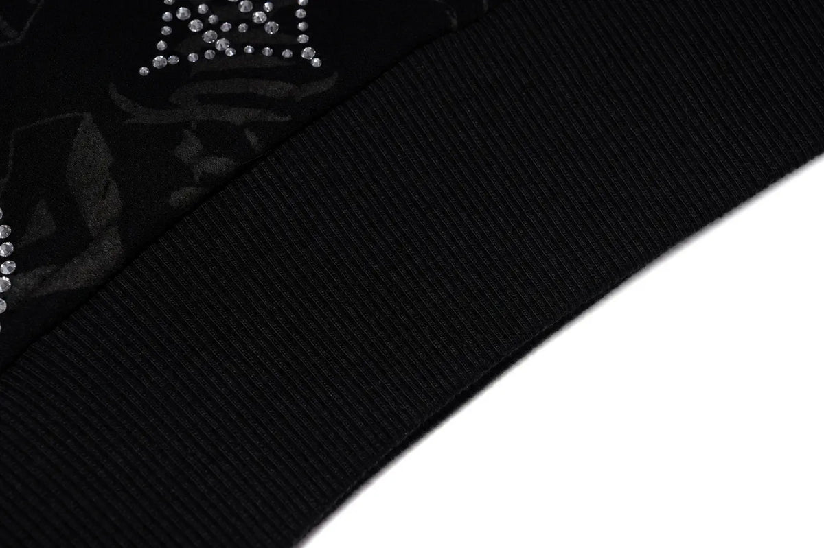 Close-up detail of a black ribbed knit fabric with a decorative crown embellishment made of small silver rhinestones on a black background. TCH Black Rhinestone Monogram Zip Up Hoodie Jacket