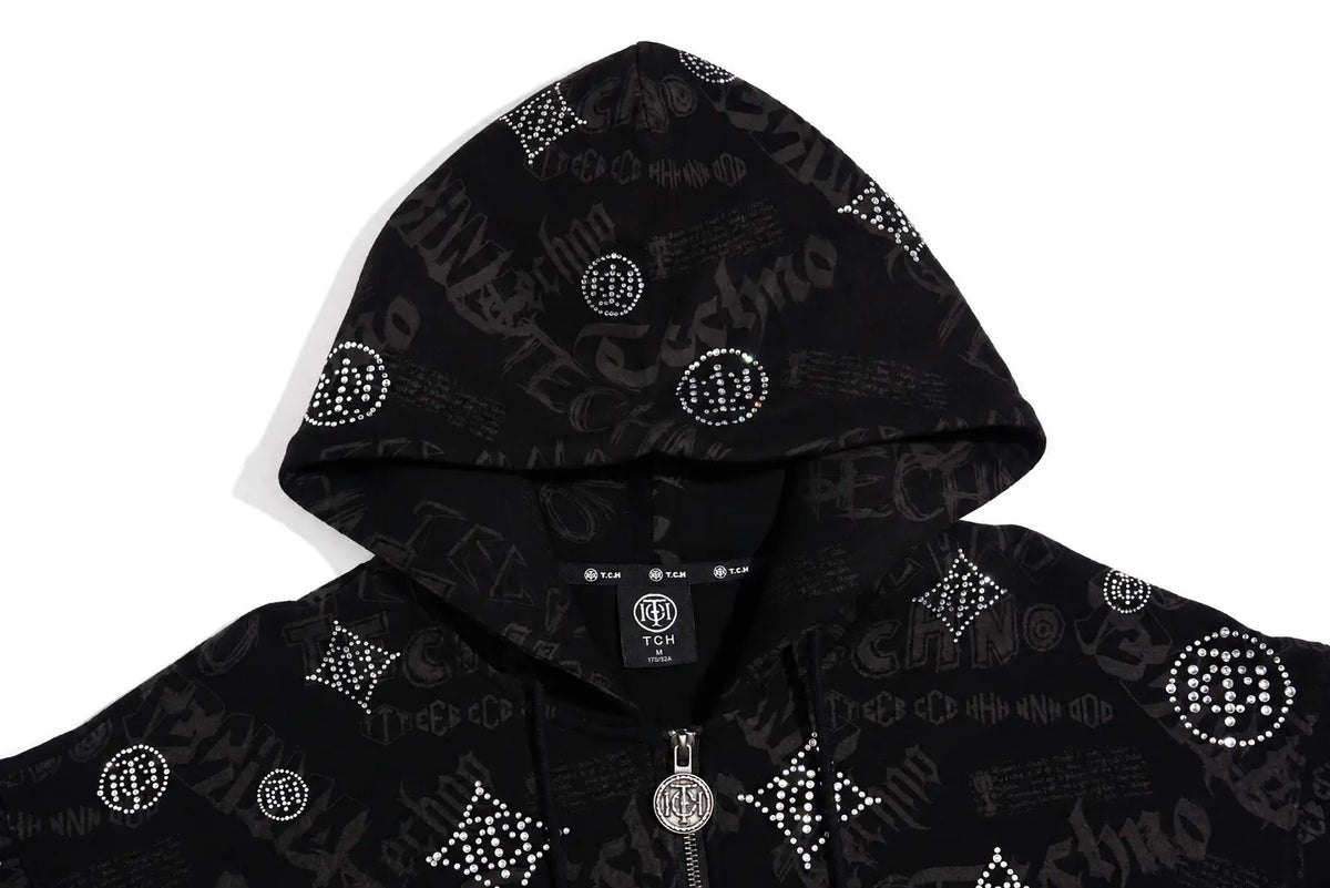 A black zip-up hoodie featuring an all-over monogram and script pattern embellished with silver rhinestones, shown against a plain white background. TCH Black Rhinestone Monogram Zip Up Hoodie Jacket