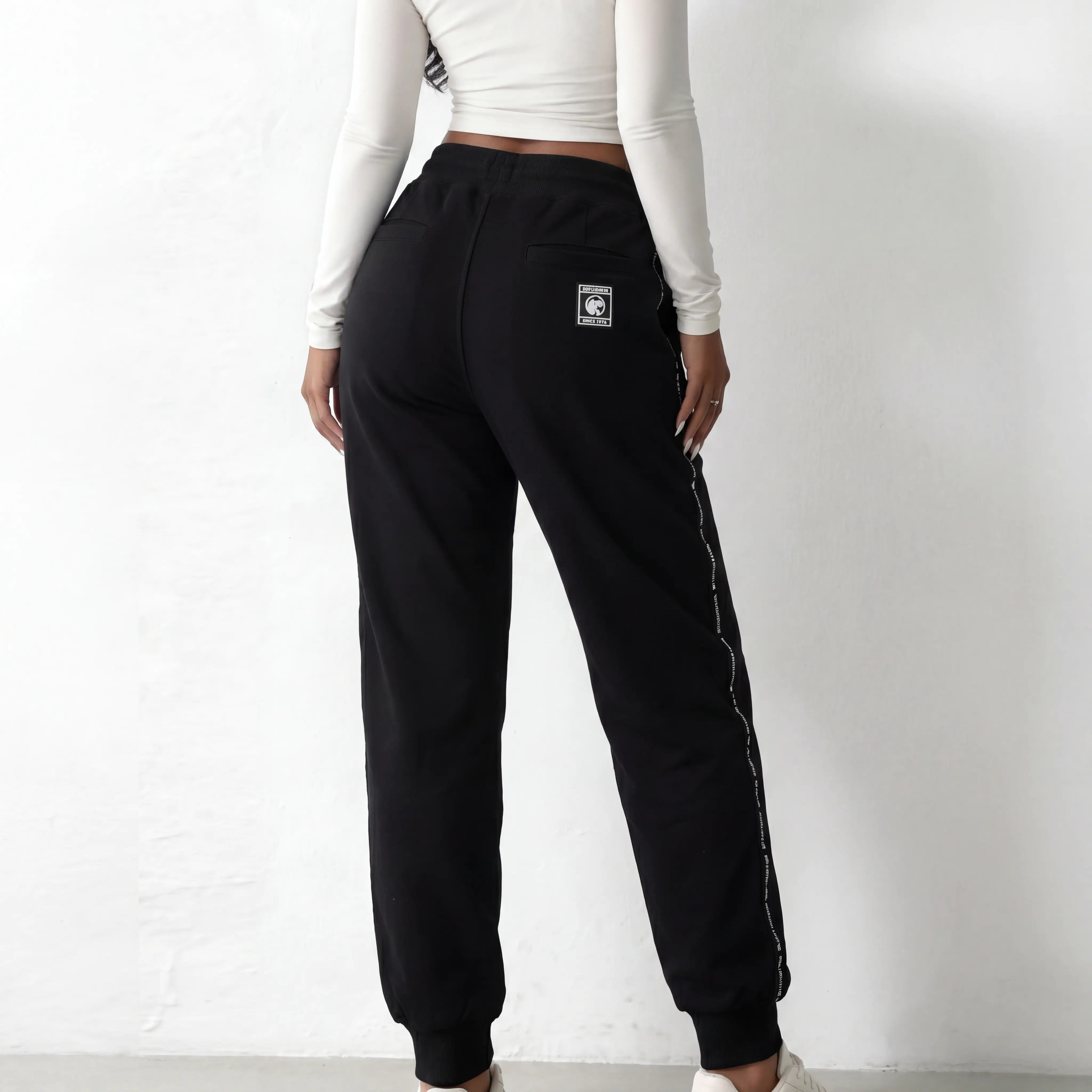 Person wearing black jogger pants with a logo on a white background, TCH Black Rhinestone Side Stripe Jogger Pants