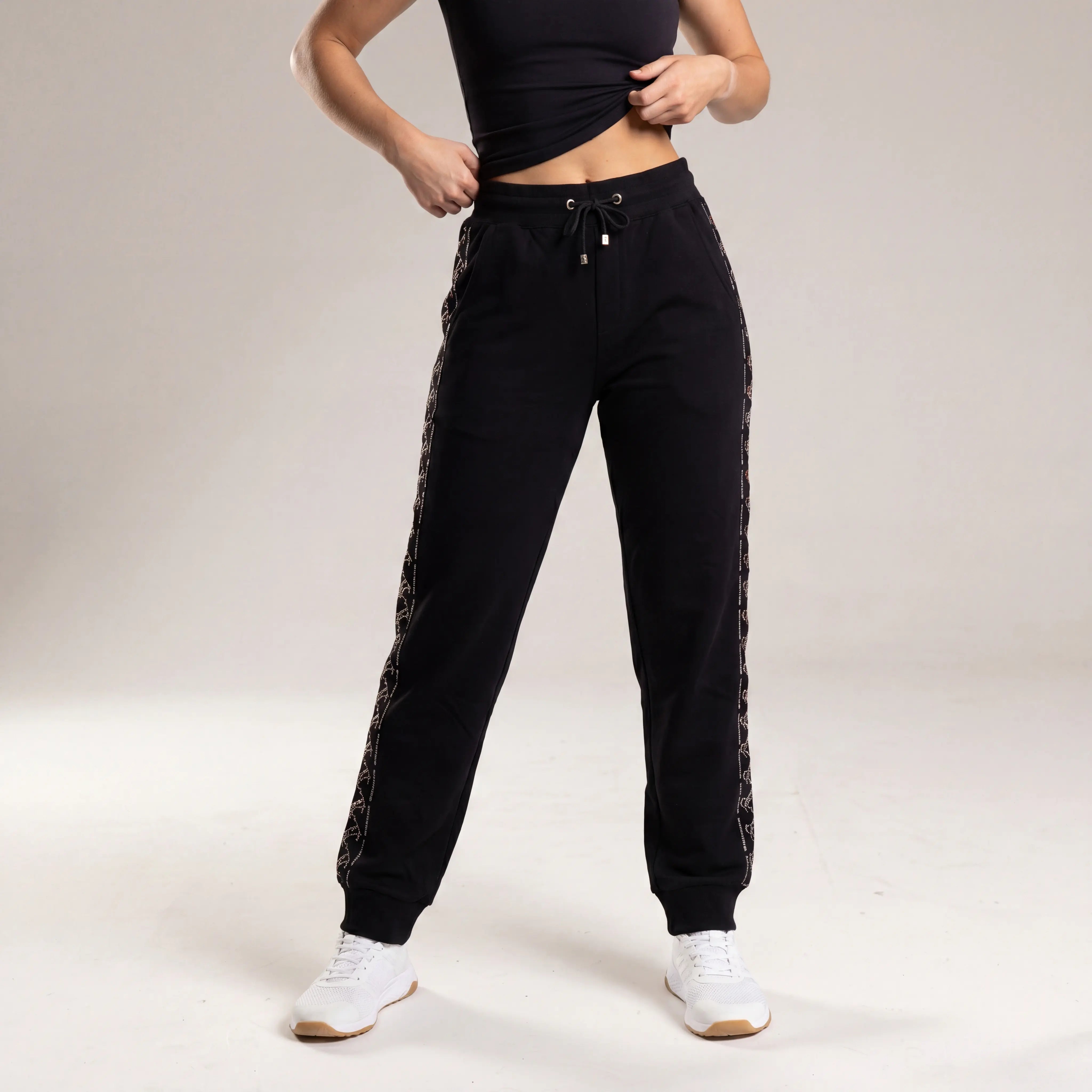 Person wearing black jogger pants with patterned side panels on a plain background, TCH Black Rhinestone Side Stripe Jogger Pants