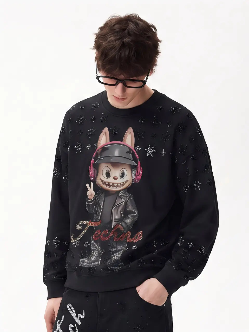 A man wearing a black crewneck sweatshirt with a graphic of a cartoon rabbit character in a leather jacket and pink headphones, with the word 'Techno' written below, set against a plain white background. TCH Black Techno Bunny Rhinestone Graphic Sweatshirt