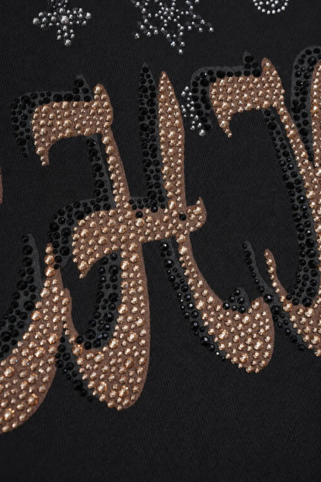 Close-up of a black garment featuring large decorative lettering embellished with metallic rose-gold rhinestones and small silver rhinestone snowflake motifs near the top. TCH Black Techno Bunny Rhinestone Graphic Sweatshirt