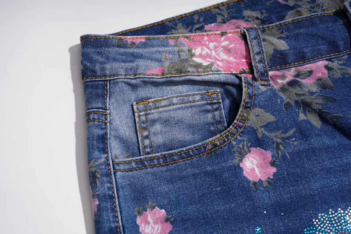 Close-up of the back pocket area of a pair of blue denim jeans with a pink and gray floral print, shown on a white background. TCH Blue Floral Butterfly Rhinestone Wide-Leg Jeans