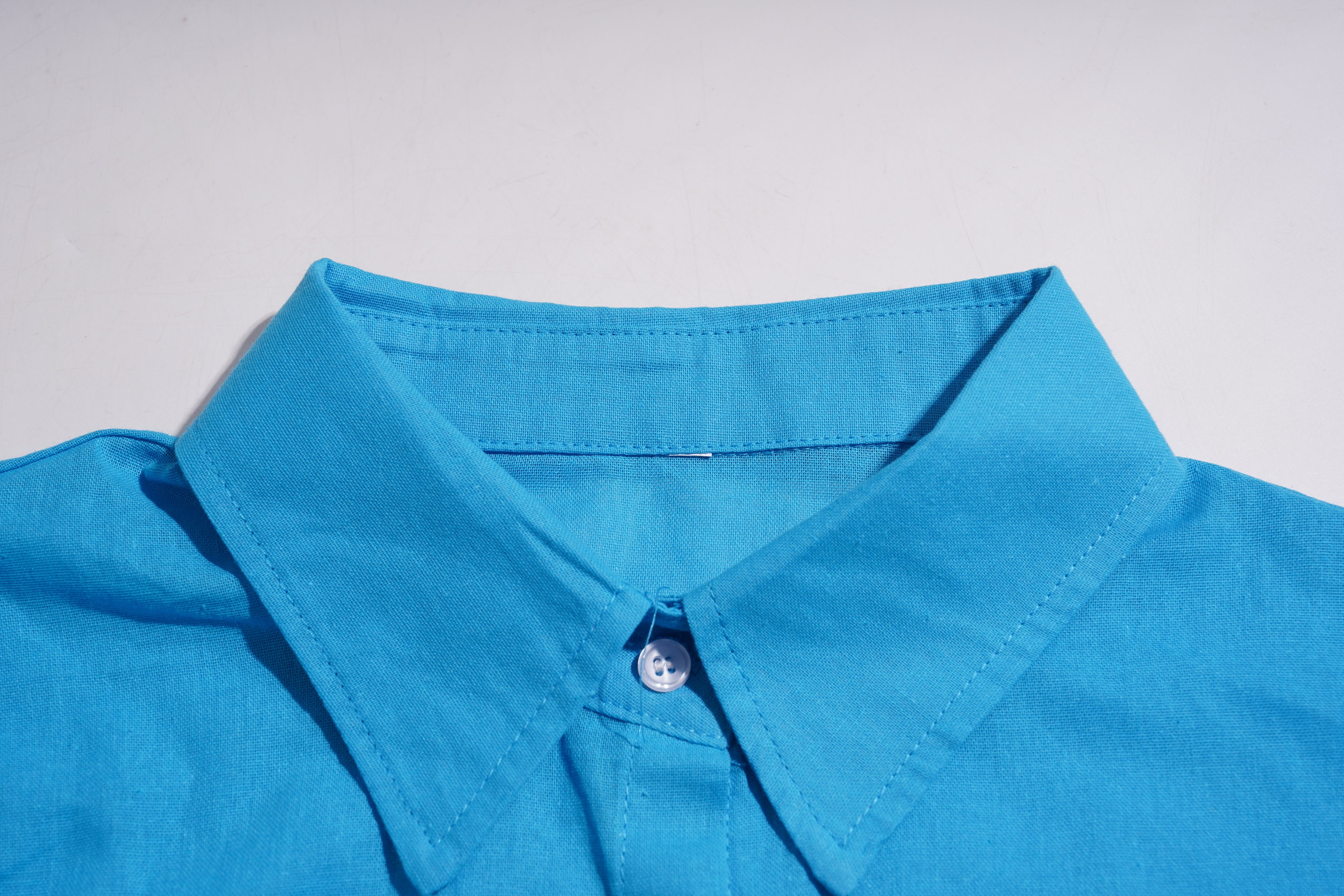 Close-up of a blue shirt collar with a button on a light gray background, TCH Blue Rhinestone Bow Matching Set