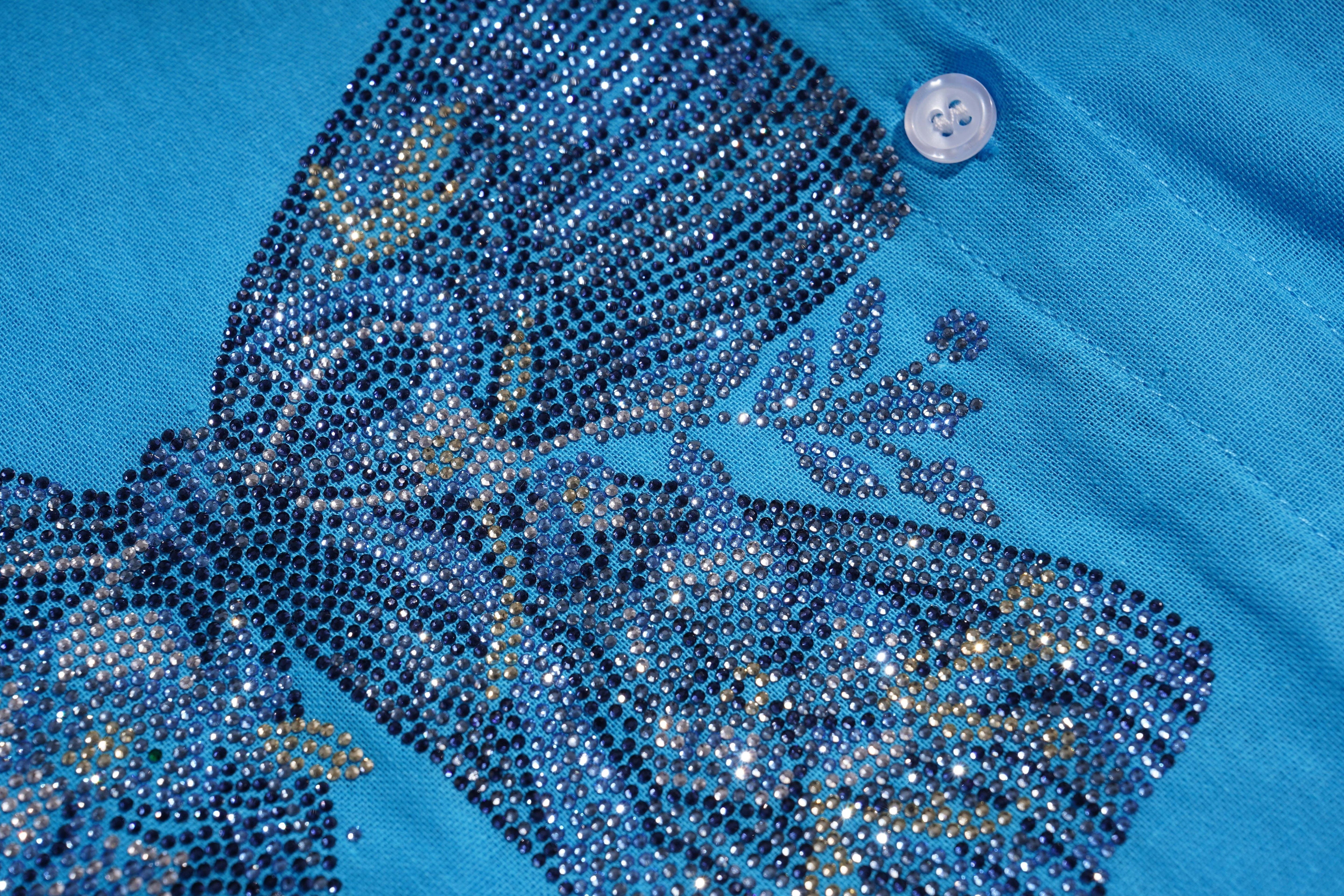Close-up of a blue garment with decorative elements and a button on a blue background, TCH Blue Rhinestone Bow Matching Set