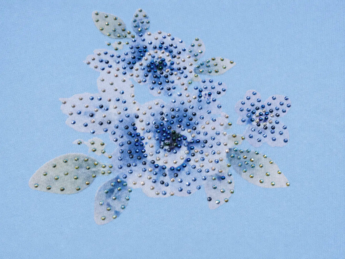 A floral rhinestone design featuring blue, white, and pale green flowers with sparkling clear and metallic beads on a light blue background. TCH Blue Teddy Bear Floral Rhinestone Hoodie