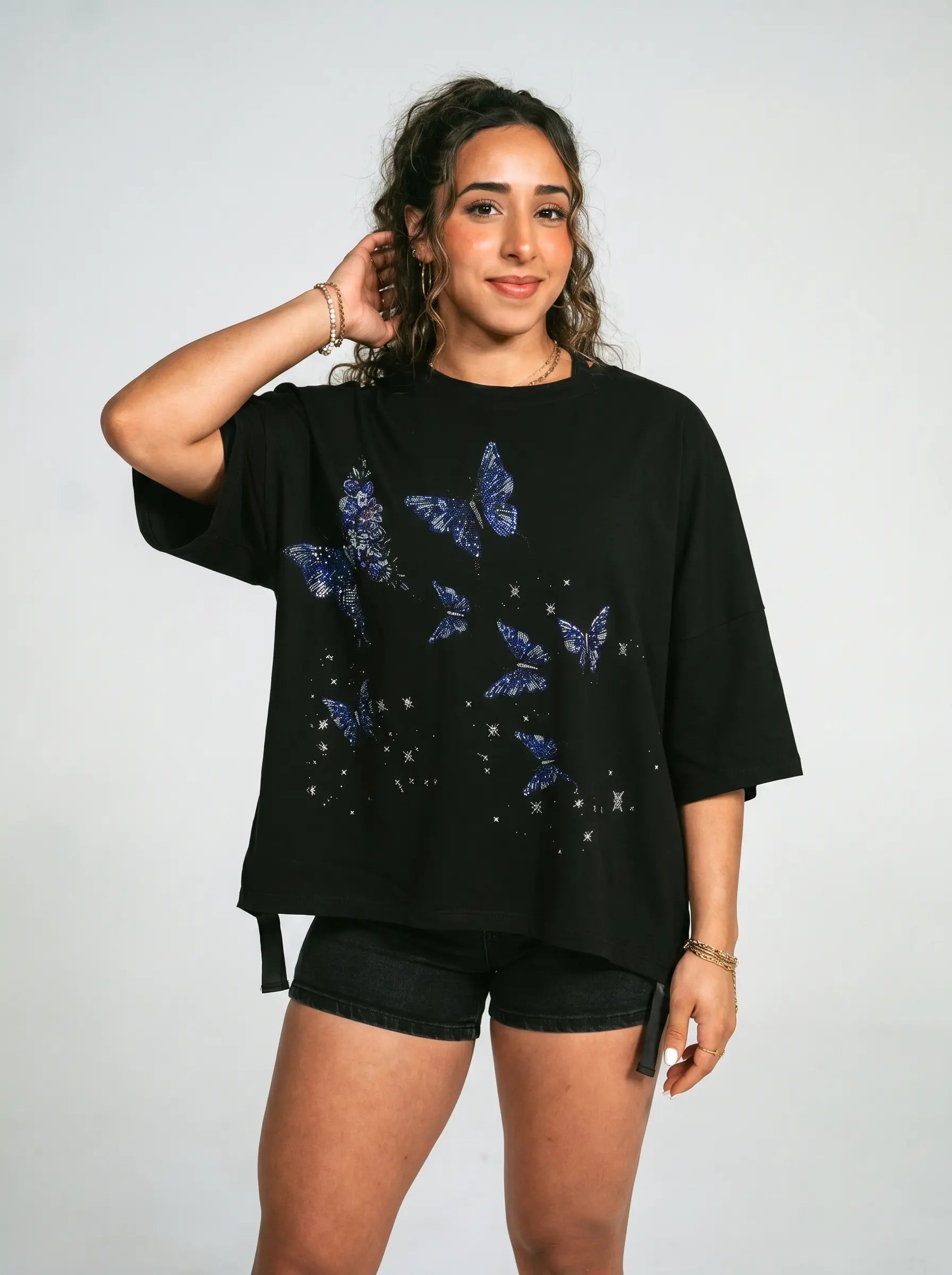 Woman wearing a black t-shirt with blue butterfly designs on a plain background, TCH Butterfly Rhinestone Oversized T-Shirt