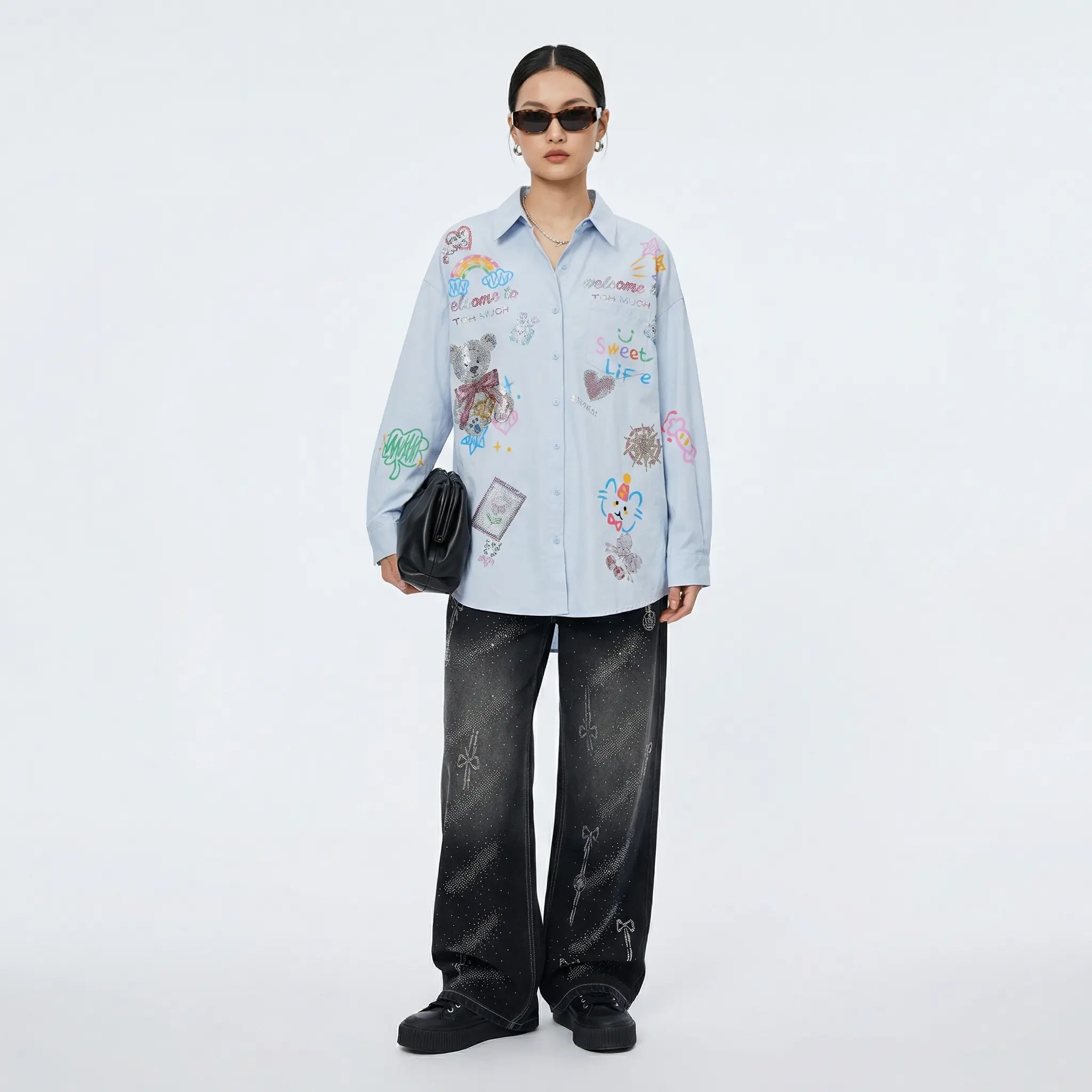 Person wearing a light blue shirt with colorful patterns and dark jeans on a white background, TCH Celestial Rhinestone Wide-Leg Black Jeans