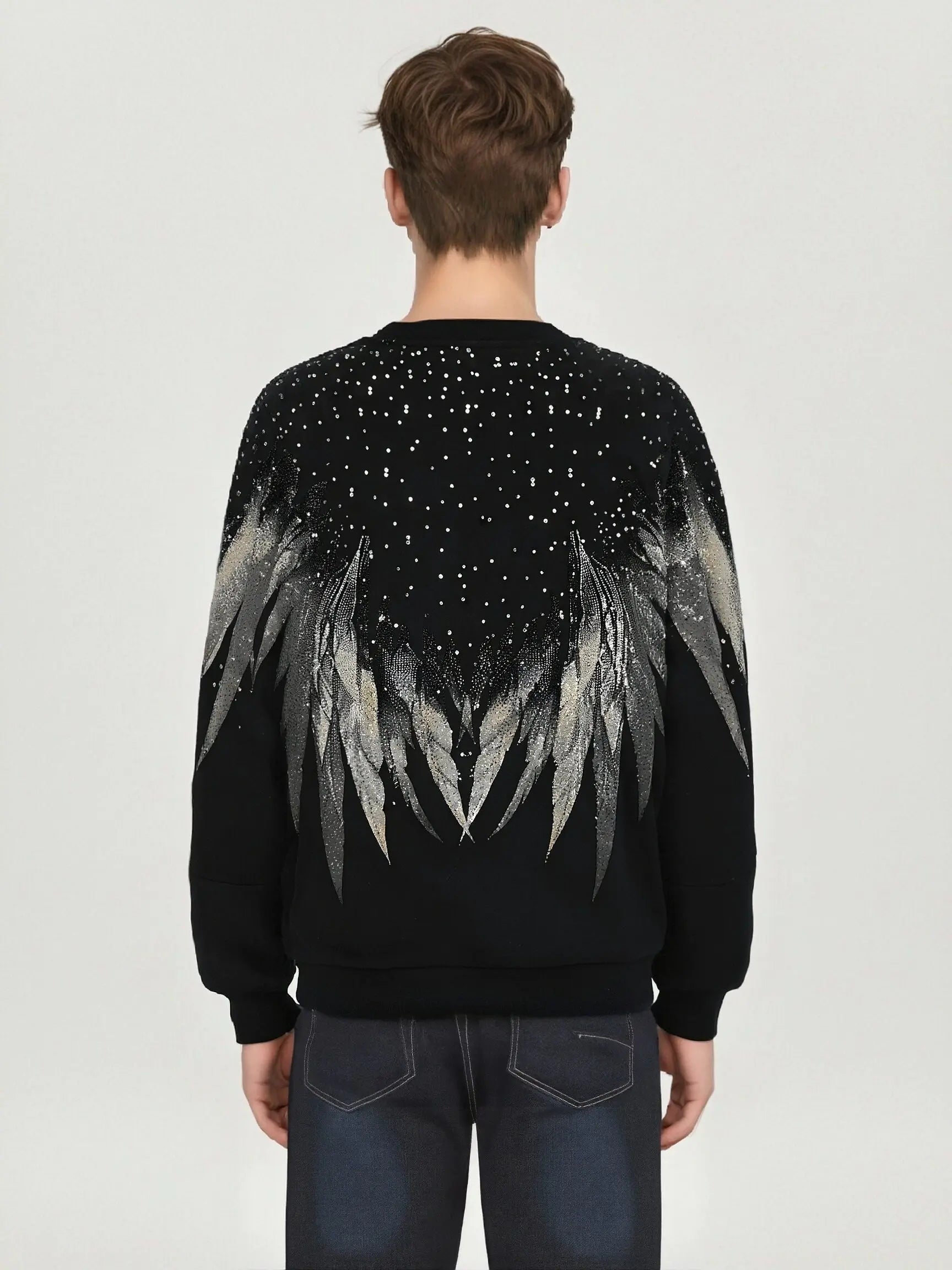 Person wearing a black sweater with feather design on the back against a light gray background, TCH Celestial Wing Graphic Crewneck Sweatshirt
