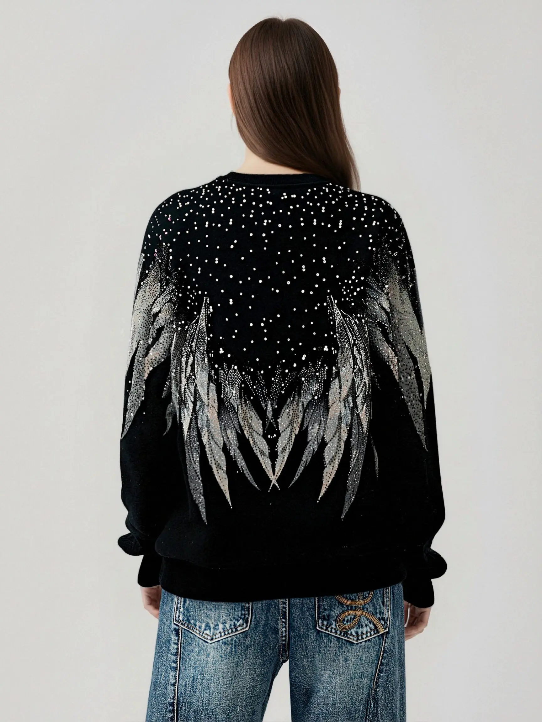Person wearing a black sweater with angel wings and starry sky design on the back. TCH Celestial Wing Graphic Crewneck Sweatshirt
