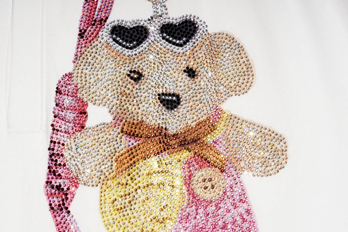 A close-up of a teddy bear embellished with rhinestones and sequins, wearing heart-shaped sunglasses, a yellow shirt, pink overalls, and a brown bow tie, set against a plain white background. TCH Crystal Bear Graphic Wide-Leg Sweatpants