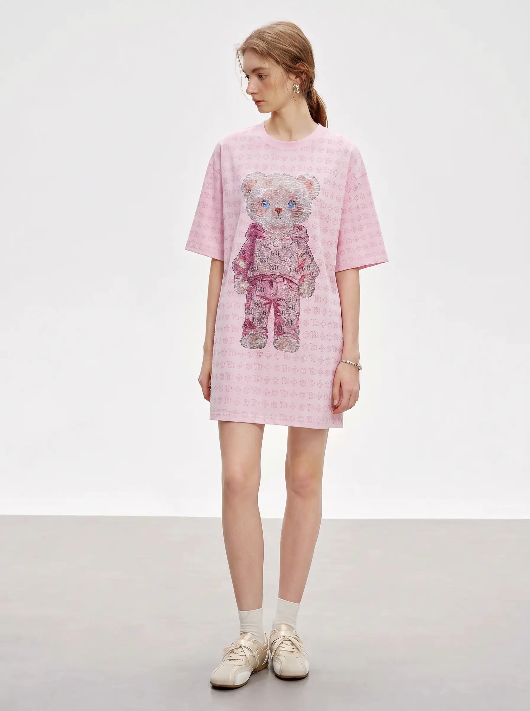 A model wearing a pink short-sleeve t-shirt dress with a teddy bear graphic, paired with white socks and beige sneakers, standing against a light gray studio background. TCH Cute Hoodie Teddy Bear Rhinestone Oversized T-Shirt Dress