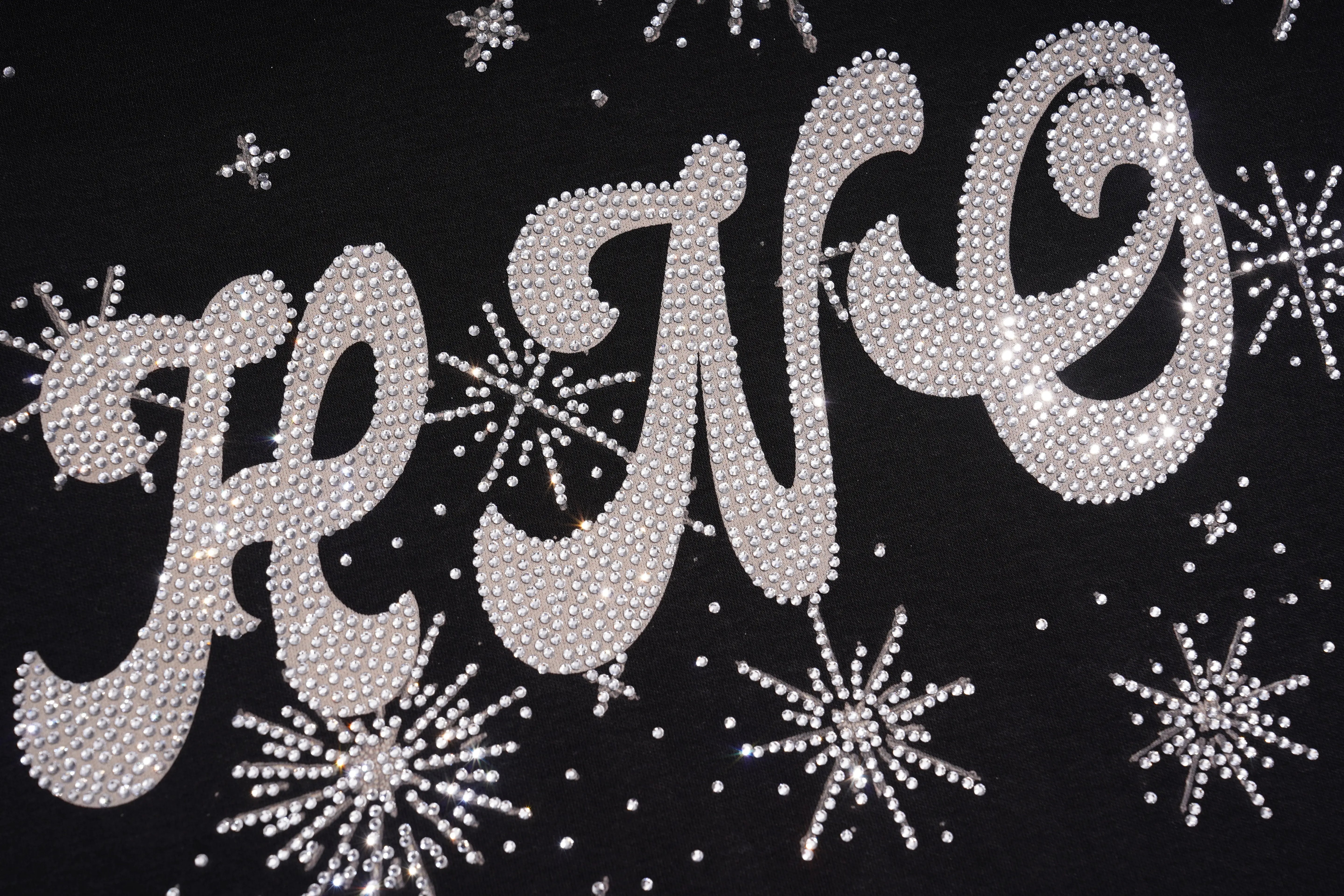 A close-up of a black garment featuring the word 'HELLO' in large, cursive letters embellished with silver rhinestones, surrounded by matching snowflake and starburst designs. TCH Cute Teddy Bear Rhinestone Oversized T-Shirt Dress