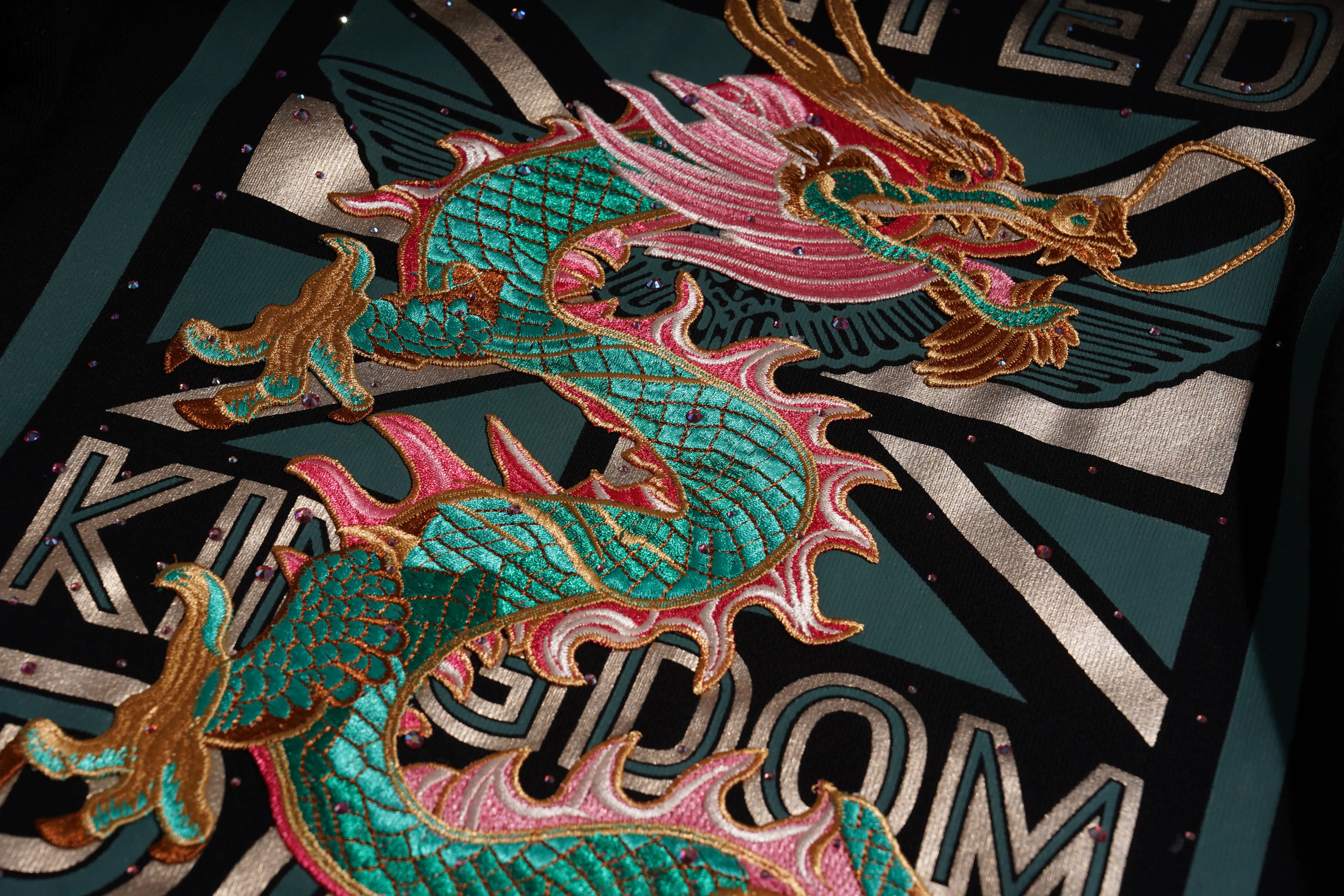Colorful dragon design on a textured surface with 'Kingsdom' branding. TCH Dragon Embroidered Rhinestone Sweatshirt-