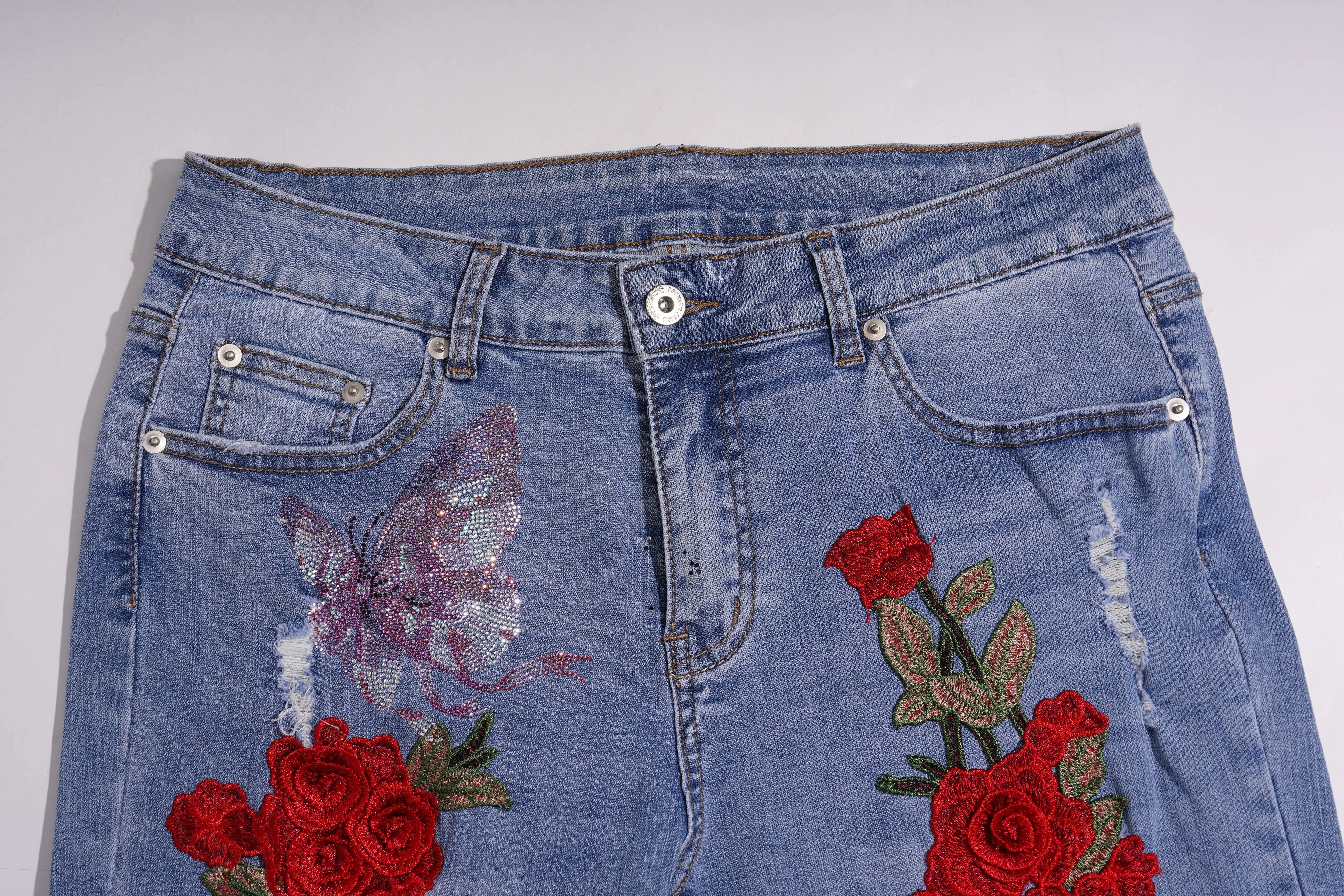Blue jeans with butterfly and rose embroidery on a white background, TCH Embroidered Rose & Rhinestone Butterfly Denim Jeans