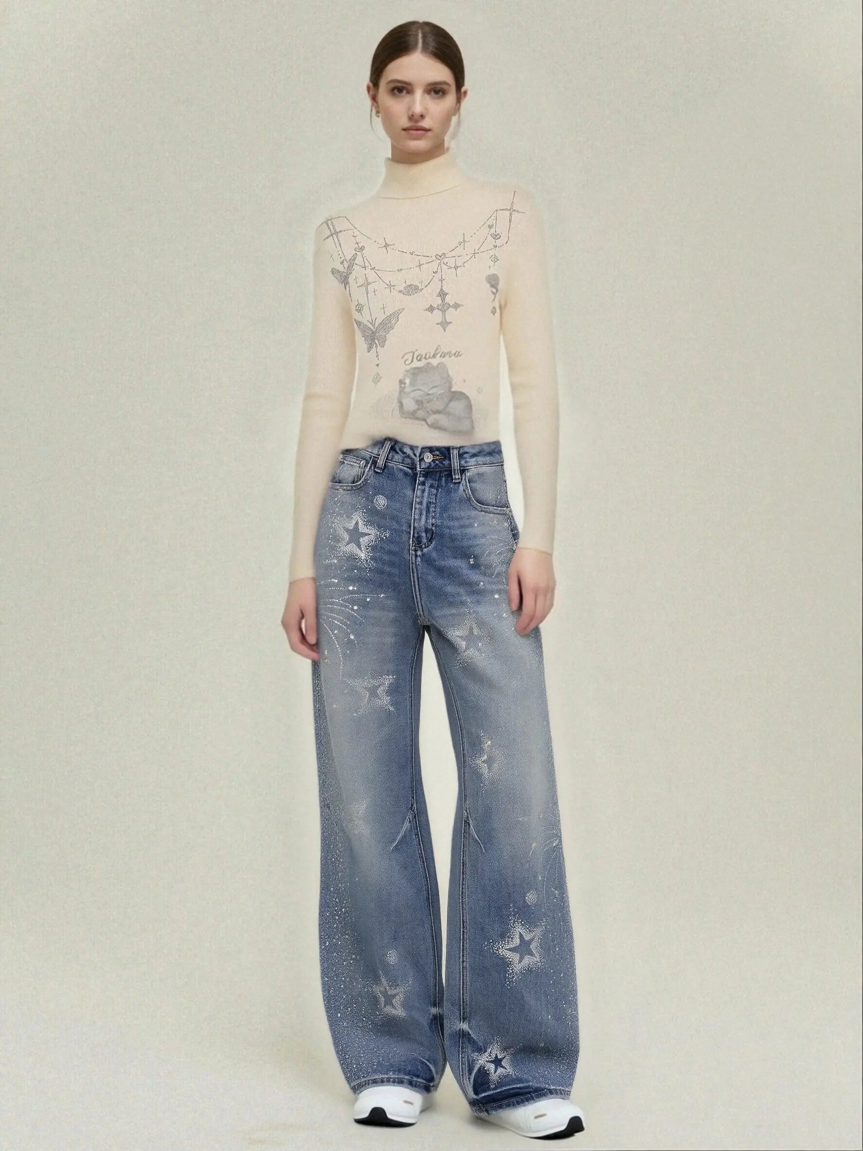 Person wearing a beige long-sleeve top with star patterns and blue jeans with star designs on a plain background, TCH Firework Star Rhinestone Straight-Leg Blue Jeans