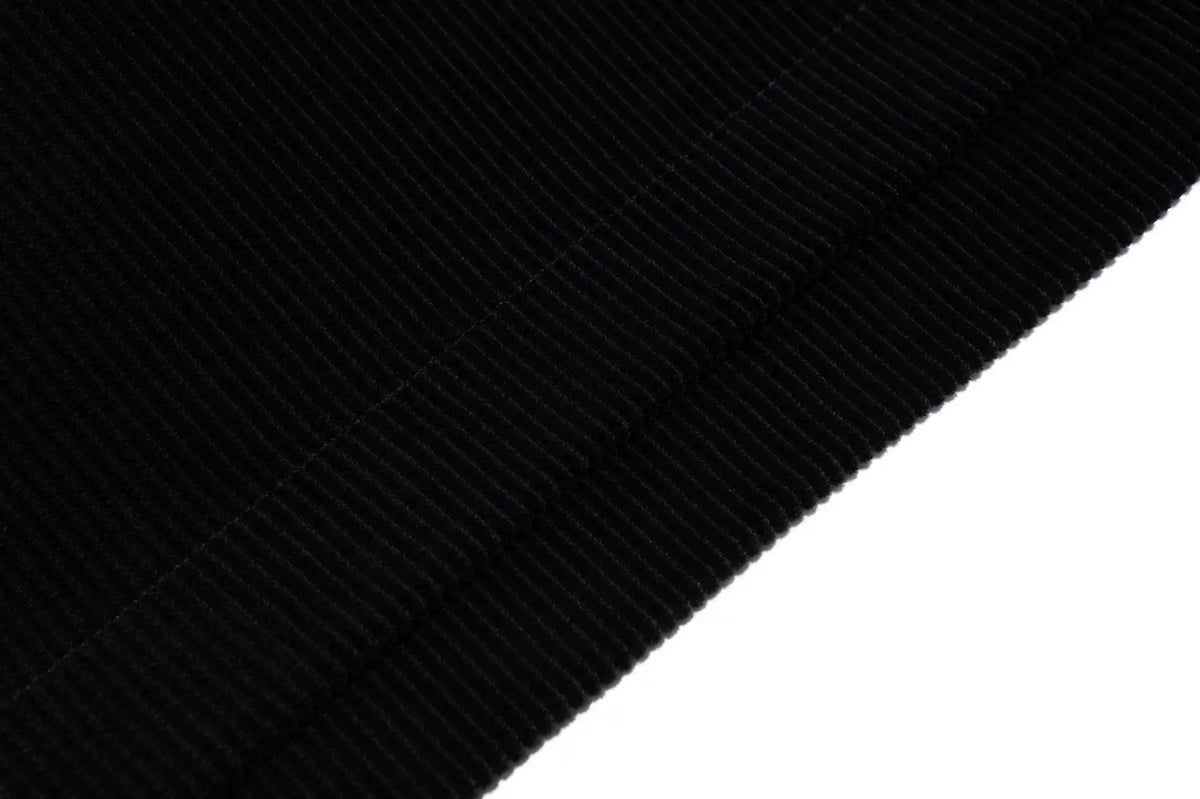 A close-up of a black ribbed fabric texture, likely a knit or corduroy material, shown diagonally against a solid white background. TCH Floral Embroidered Techno Corduroy Mini Skirt