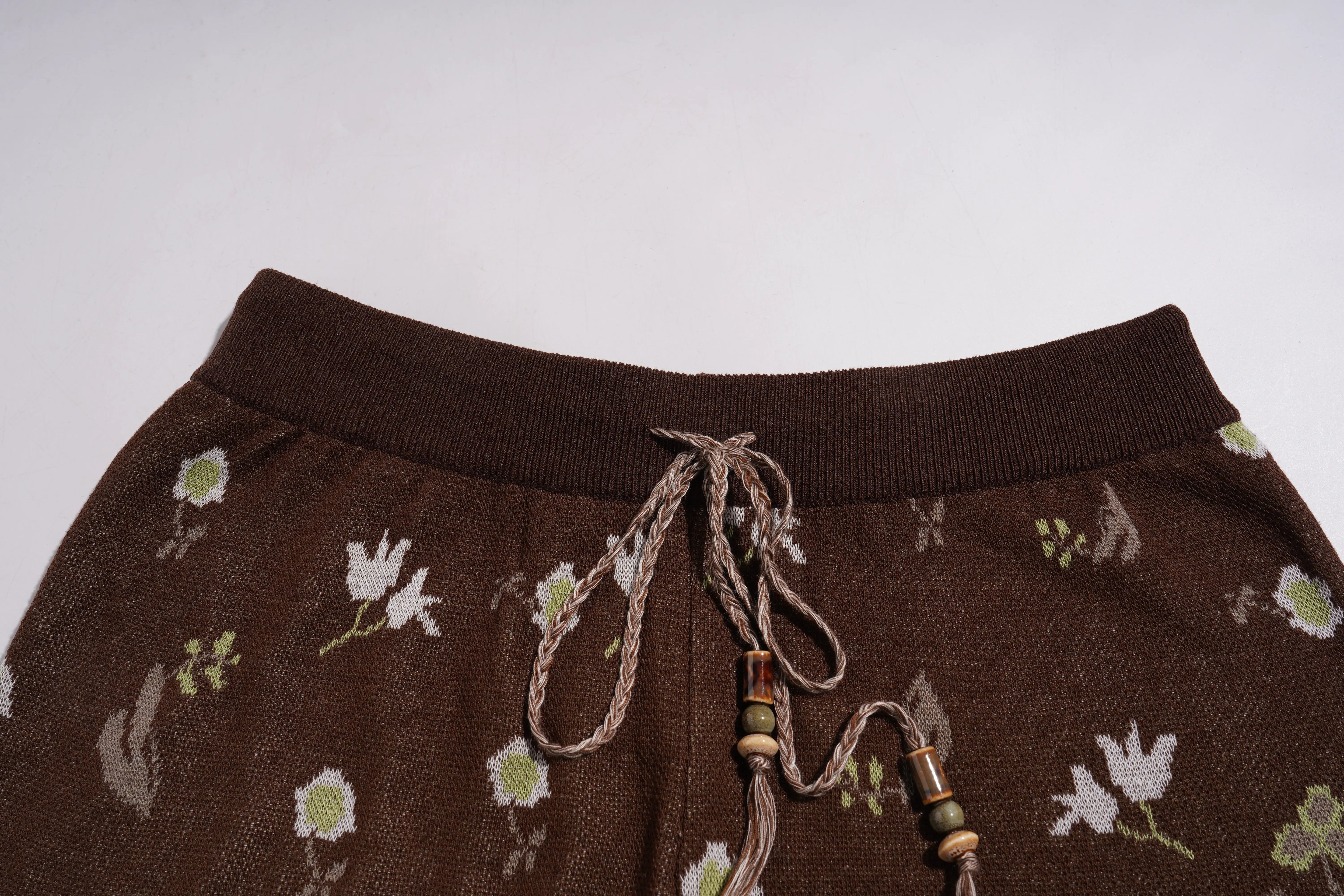 Brown pants with floral patterns and decorative strings on a light gray background, TCH Floral Rhinestone Accent Sweatpants