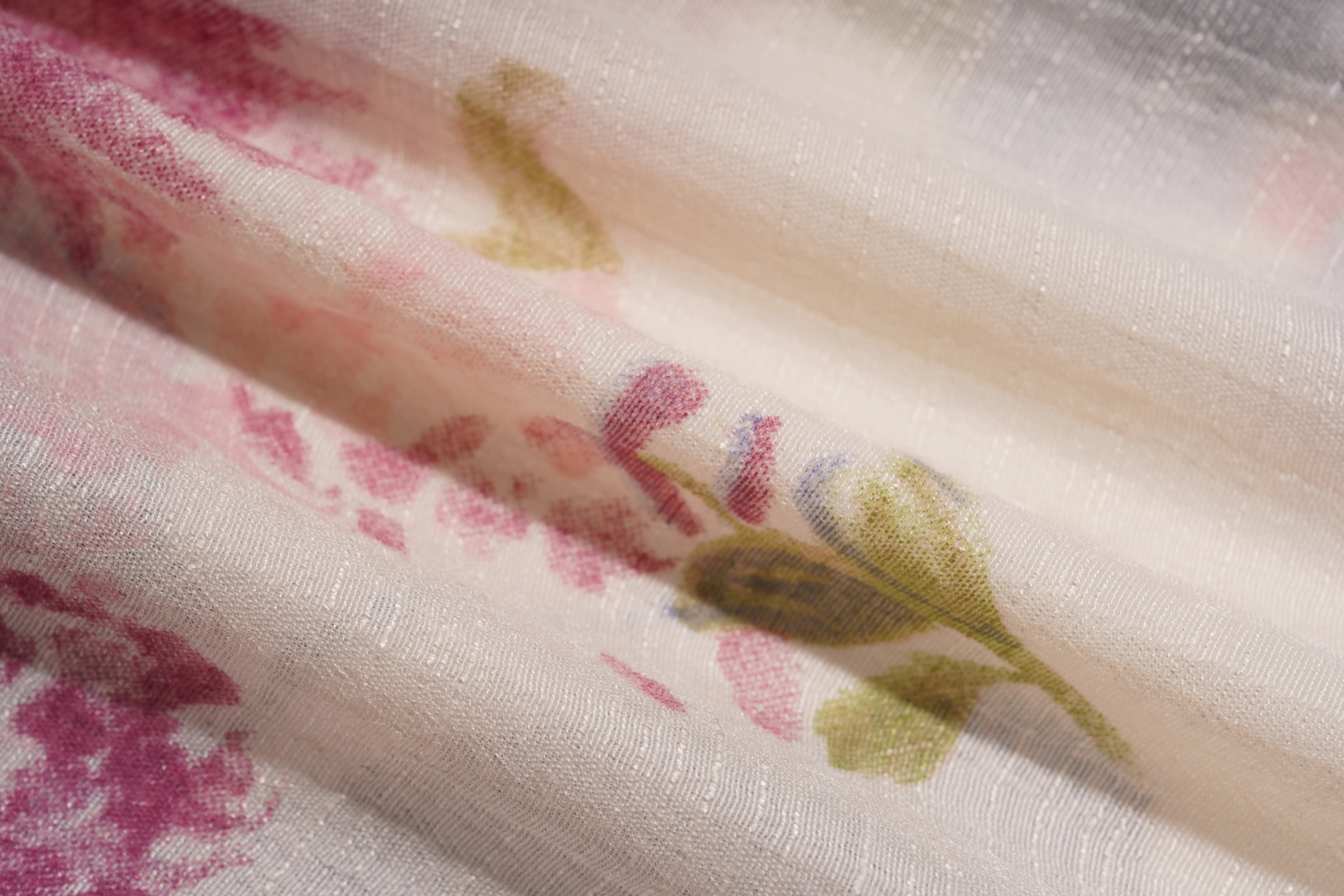 A close-up of sheer white fabric with a soft pink floral print and muted olive-green leaf details, draped in gentle folds. TCH Floral Rhinestone Butterfly Print Short Sleeve Blouse
