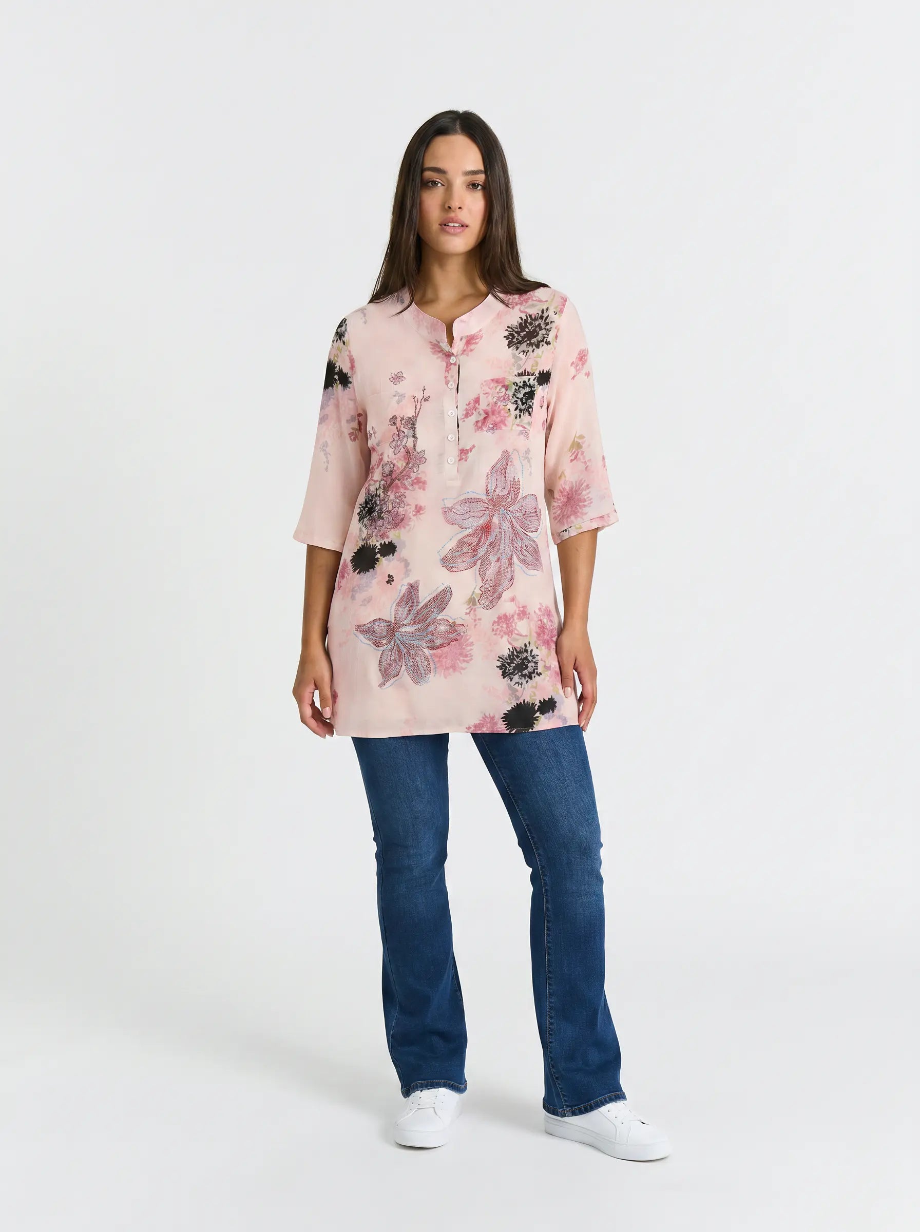 A woman modeling a light pink floral tunic top with three-quarter sleeves, paired with blue jeans and white sneakers, against a plain white studio background. TCH Floral Rhinestone Butterfly Print Short Sleeve Blouse