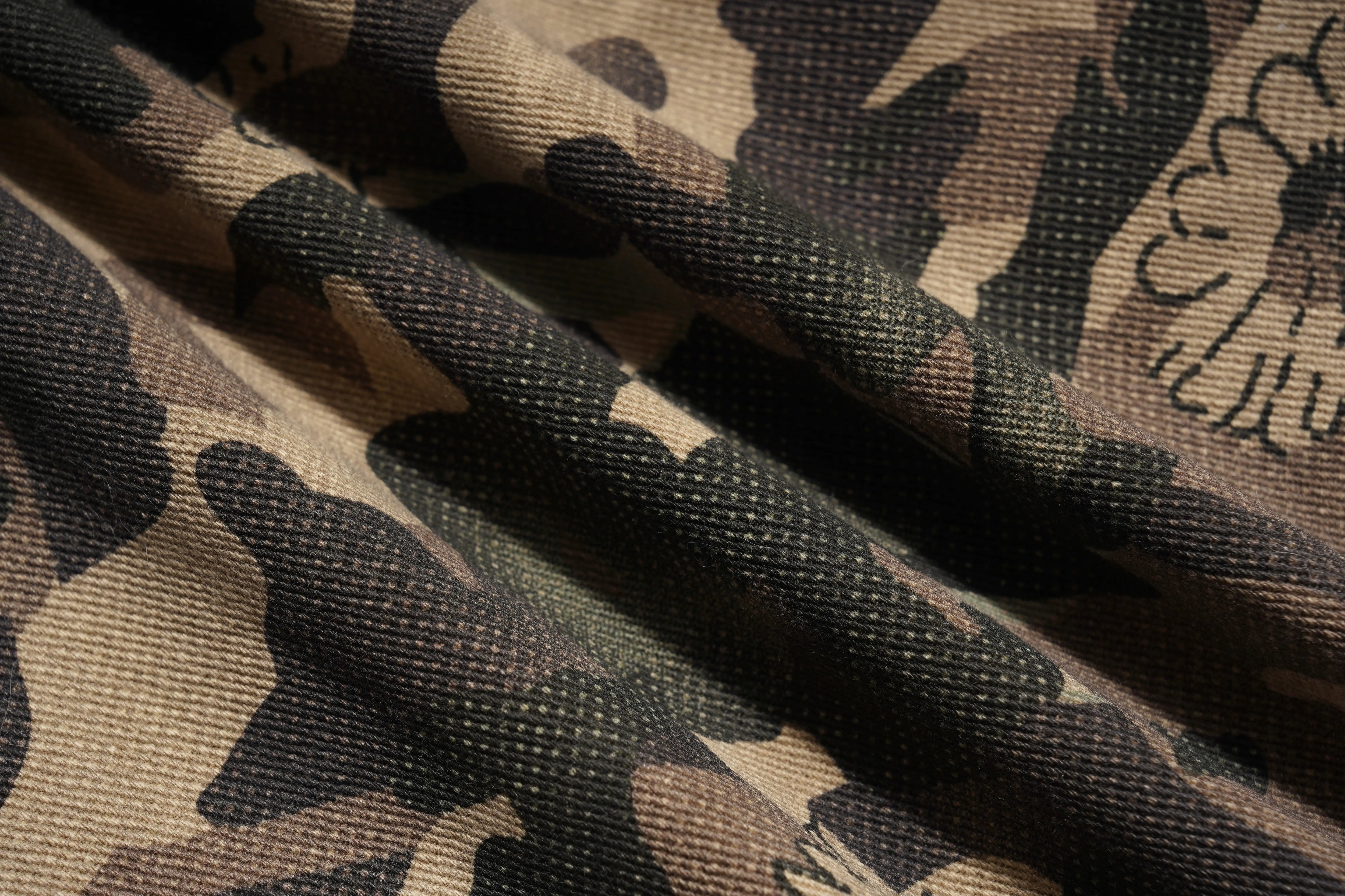 Close-up of camouflage fabric with a detailed pattern, TCH Gold Snowflake Rhinestone Camo Denim Jeans