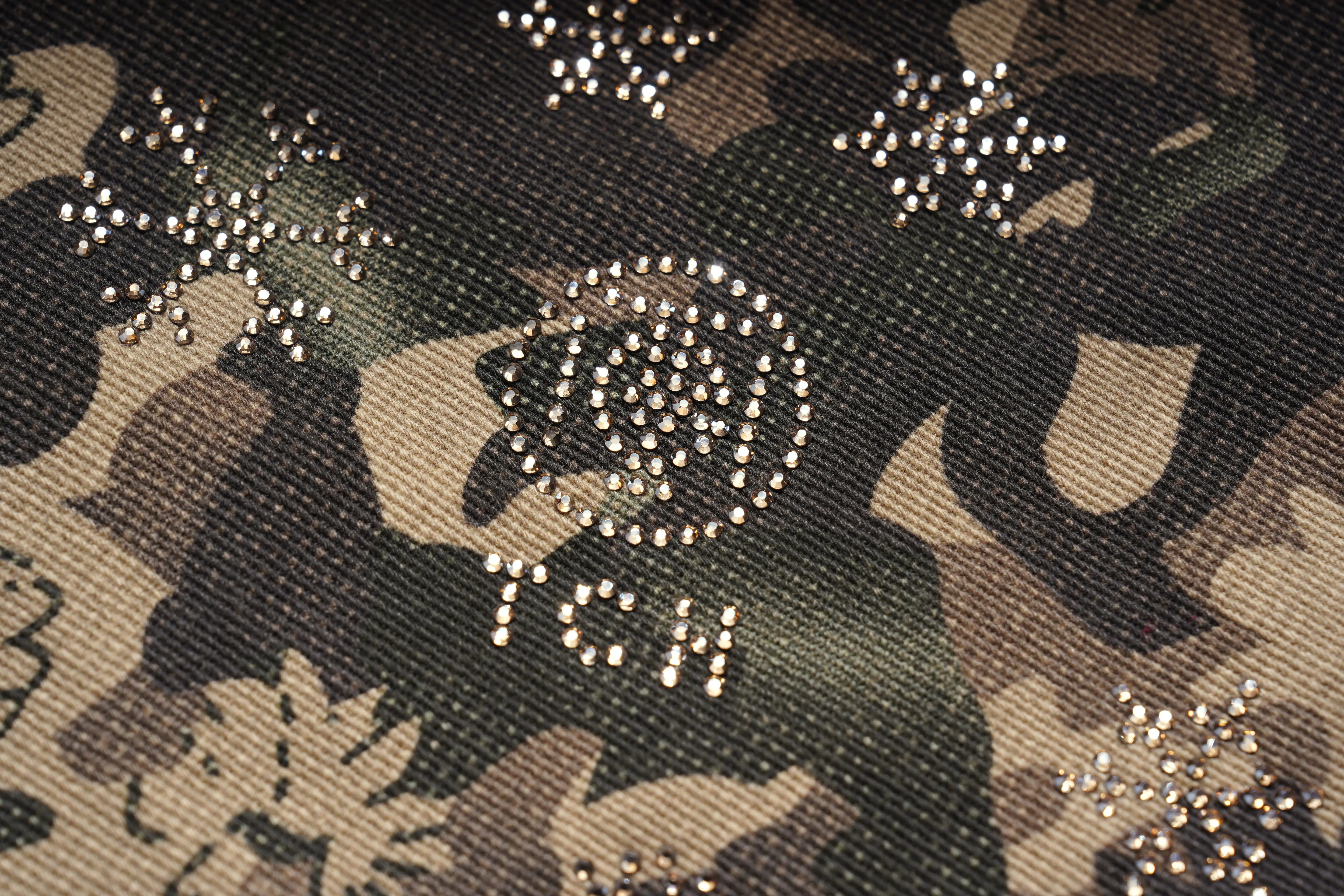 Camouflage fabric with rhinestone embellishments and a logo. TCH Gold Snowflake Rhinestone Camo Denim Jeans