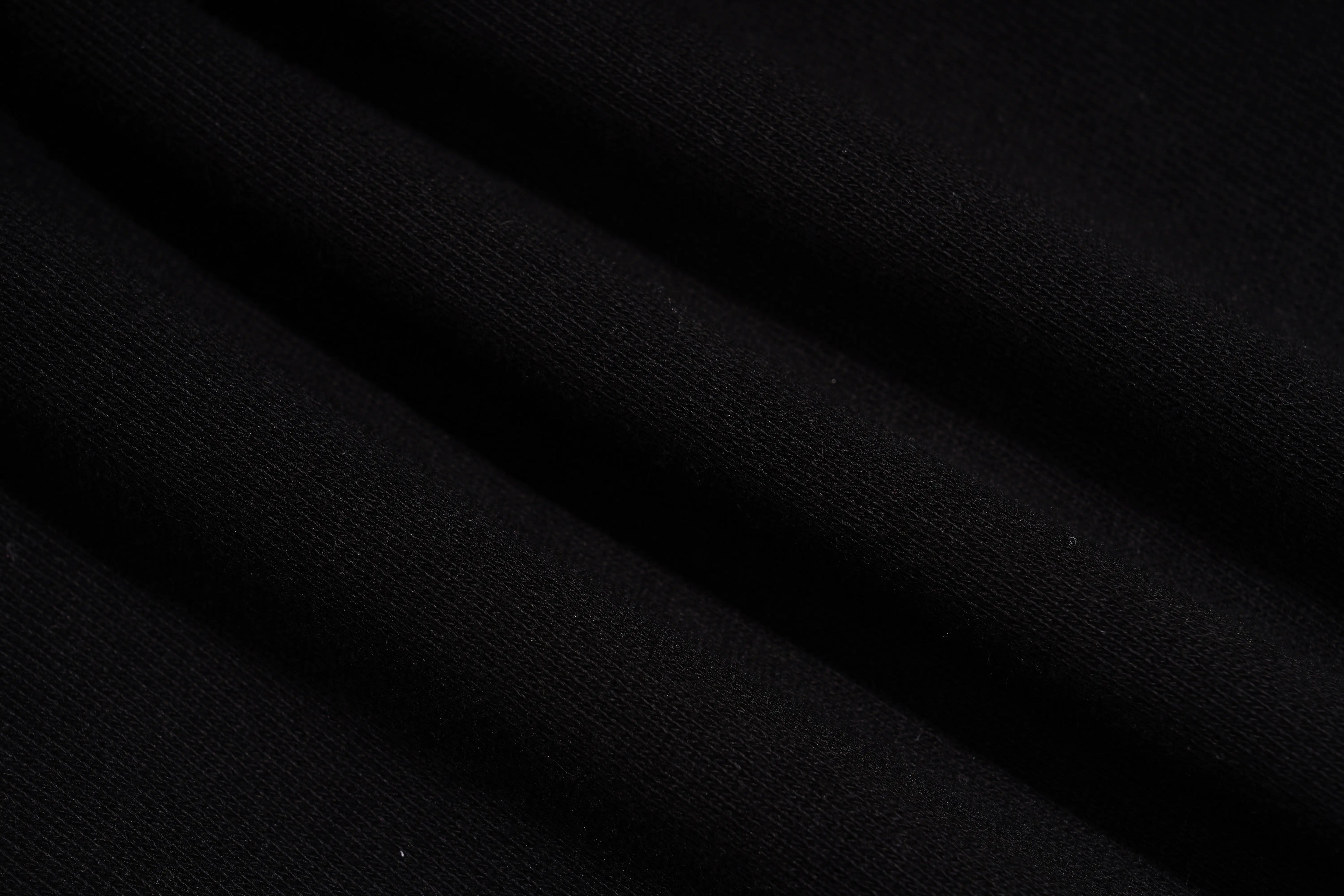 A close-up of draped black fabric with soft folds showing a fine knit texture. TCH Gothic Rhinestone Teddy Bear Chain Print Sweat Shorts