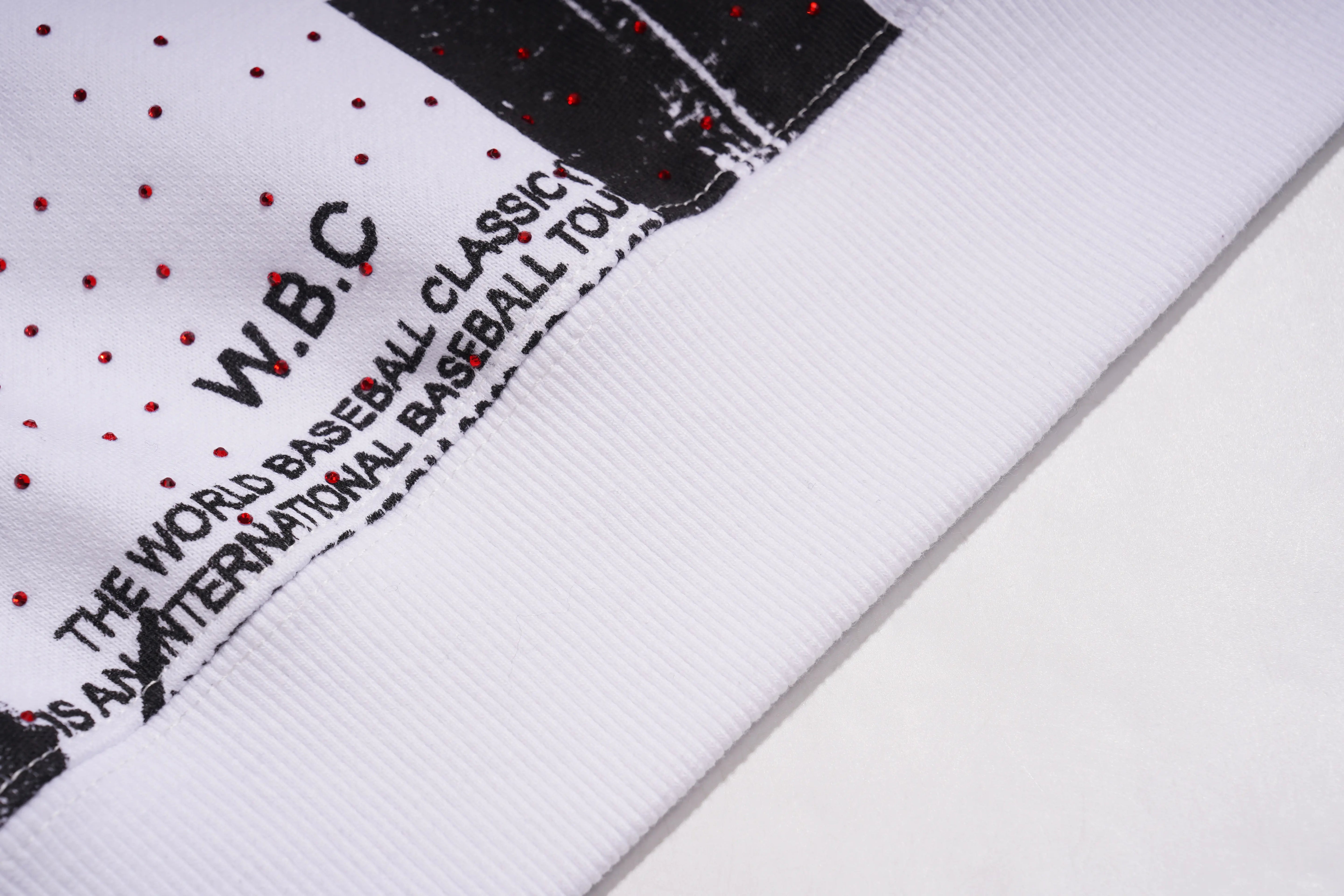 Close-up of a white sports jersey with black text and red dots, featuring 'W.B.C.' and 'World Baseball Classic'. TCH Graffiti Logo Print Crewneck Sweatshirt
