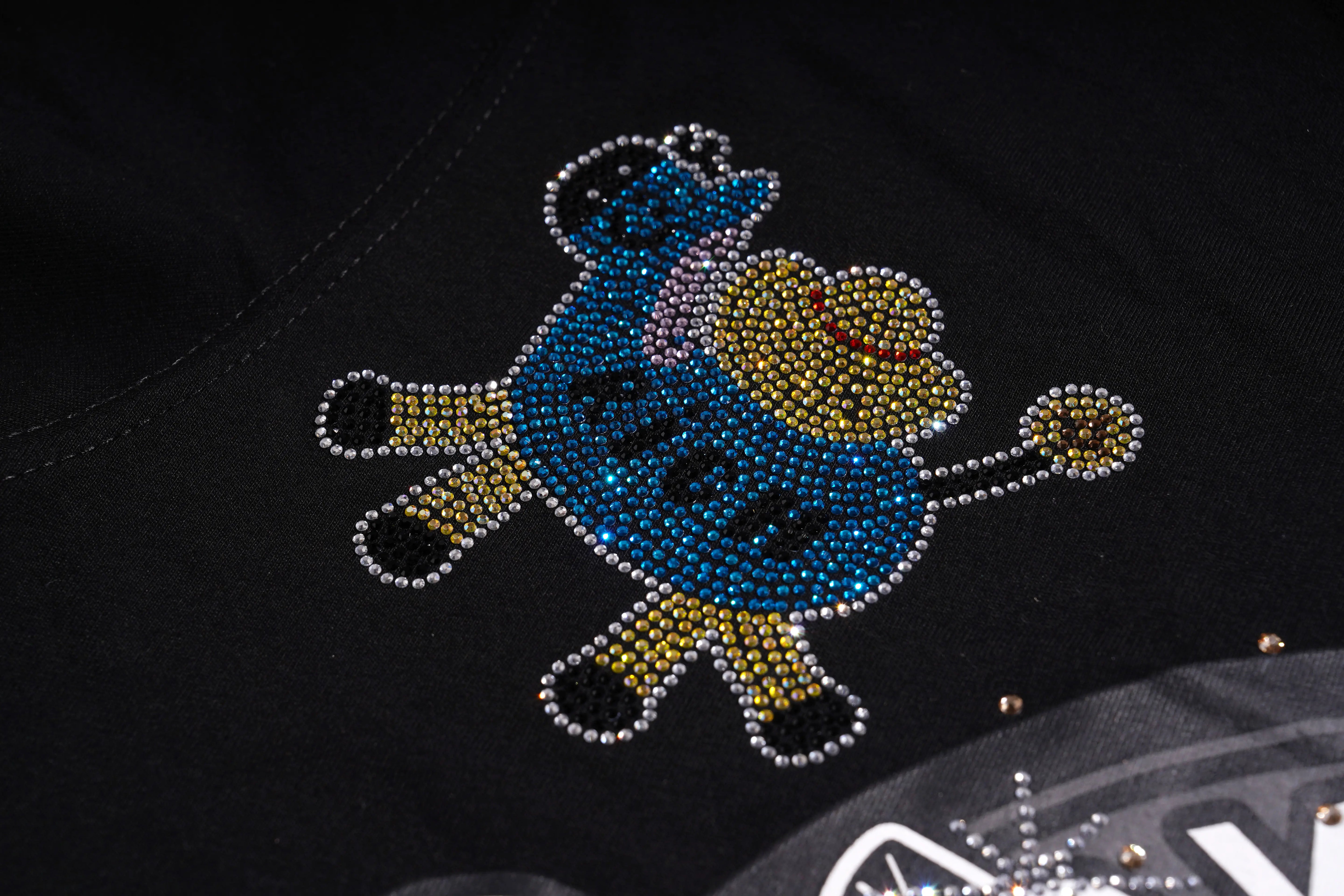 Decorative design on a black surface with rhinestones and text. TCH Graphic Rhinestone Heat Transfer Crewneck Sweatshirt-