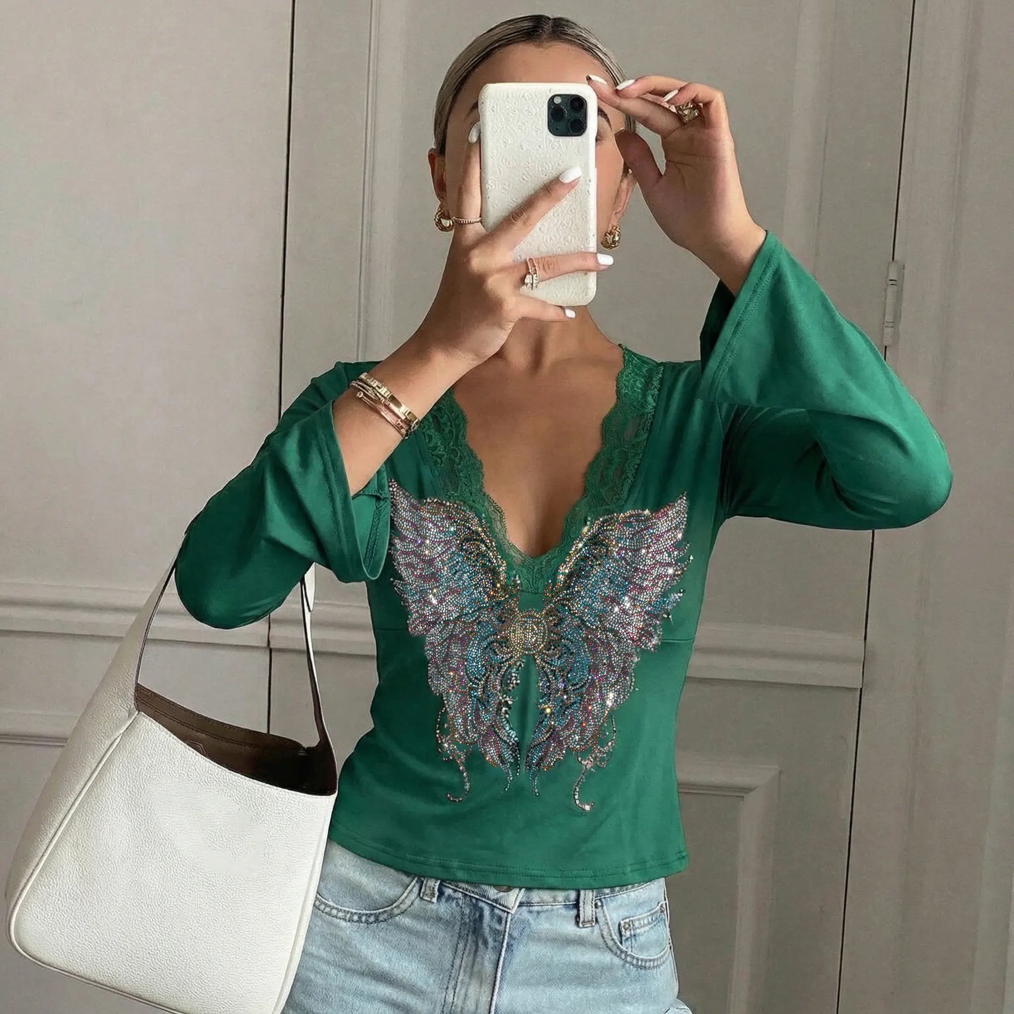 Person wearing a green blouse with a butterfly design, taking a mirror selfie. TCH Green Lace Trim V-Neck Rhinestone Wing Long Sleeve Top