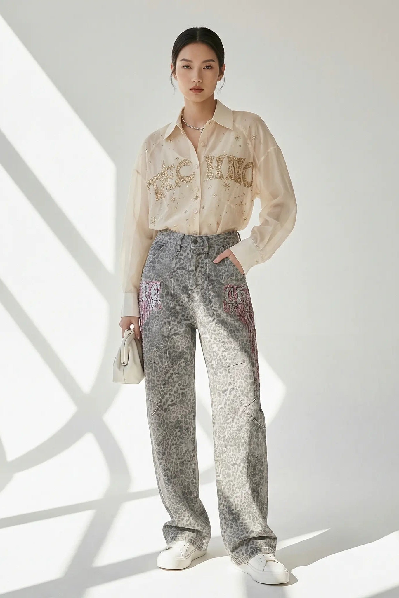 Person wearing a light-colored shirt and patterned pants standing against a white background, TCH Grey Leopard Rhinestone Wings Wide-Leg Jeans