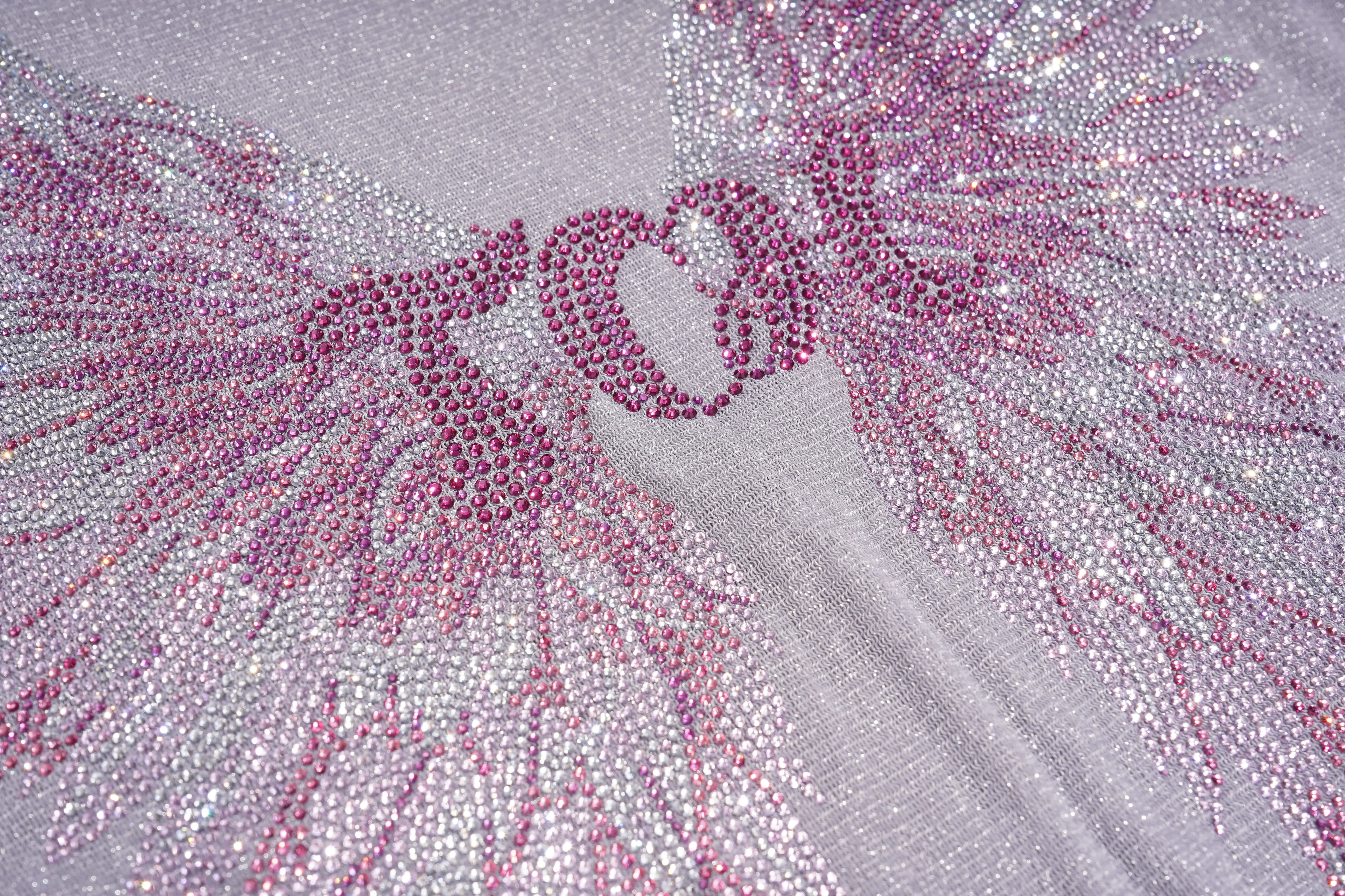 Close-up of a textured surface with pink and silver embellishments, TCH Grey Rhinestone Purple Wings Long Sleeve Top
