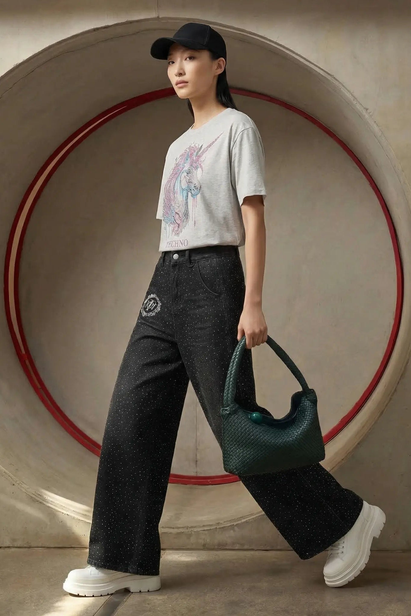Woman holding a green handbag in front of a large circular concrete structure. TCH Grey Rhinestone Unicorn Graphic T-Shirt