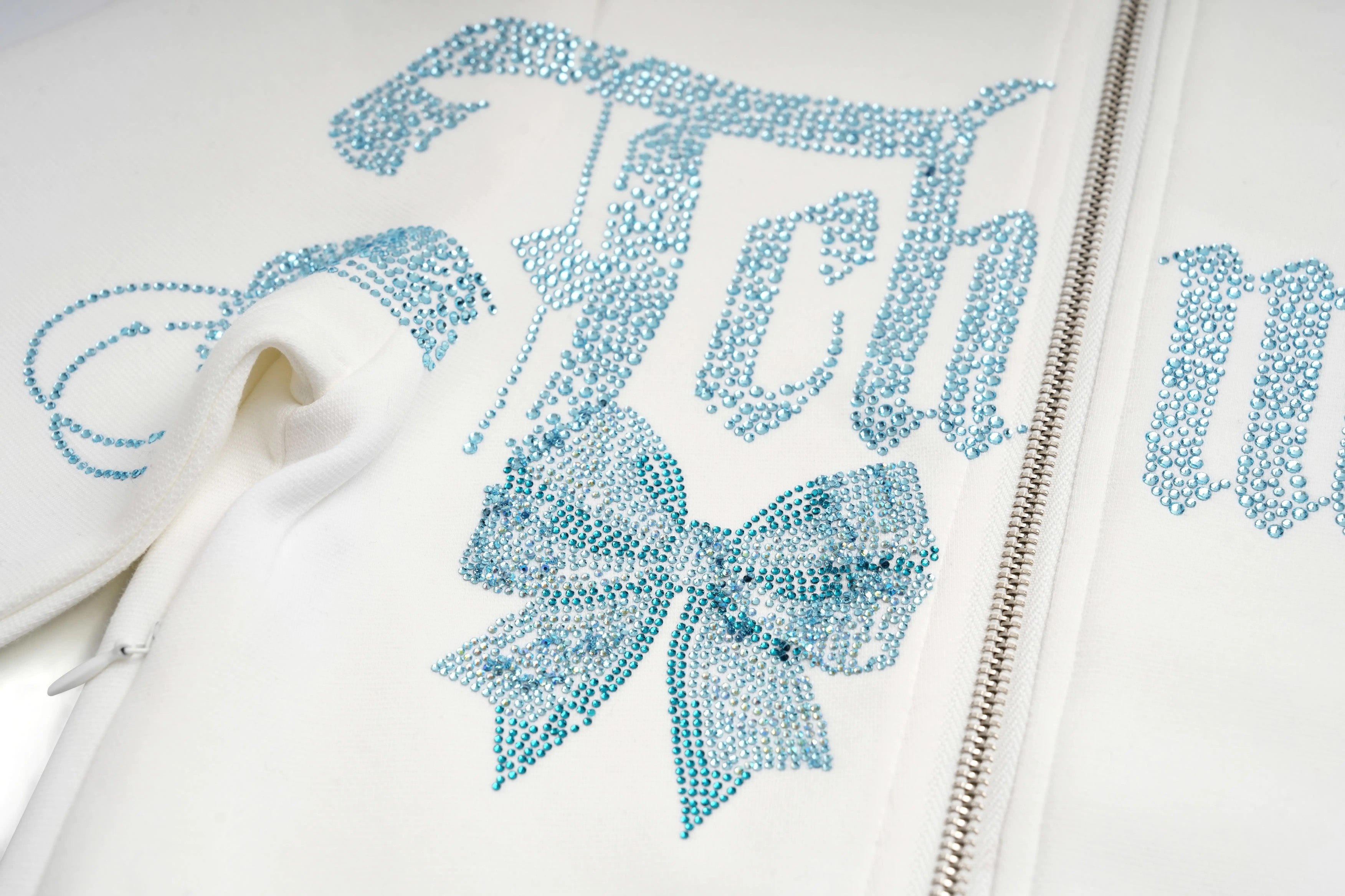 White hoodie with blue rhinestone embellishments on a white background, TCH Ice Blue Rhinestone Bow Zip-Up Jacket