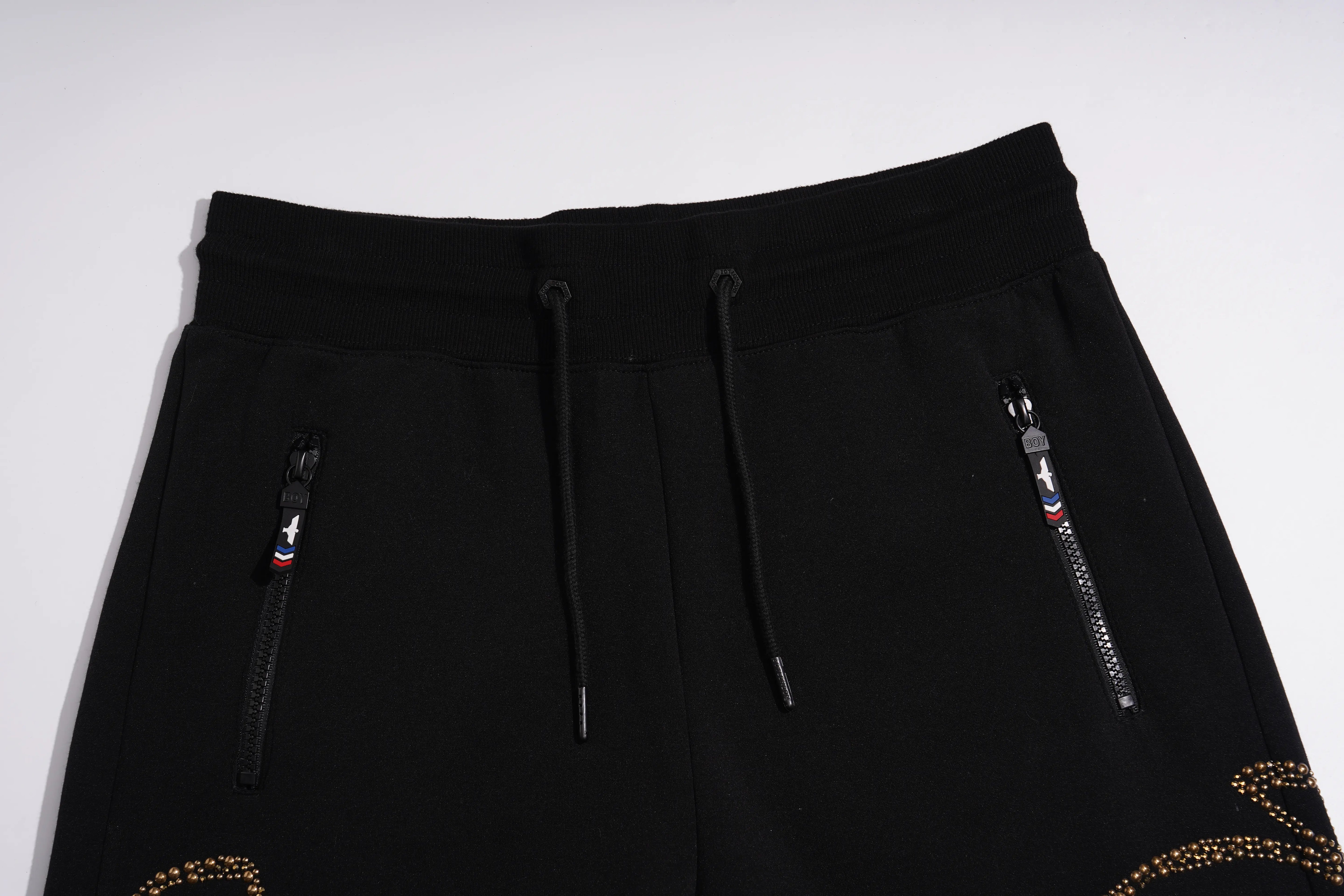 Black drawstring sweatpants with two zippered pockets and gold rhinestone embellishments near the lower legs, shown against a plain light background. TCH Luxury Rhinestone High Heel Graphic Black Sweatpants