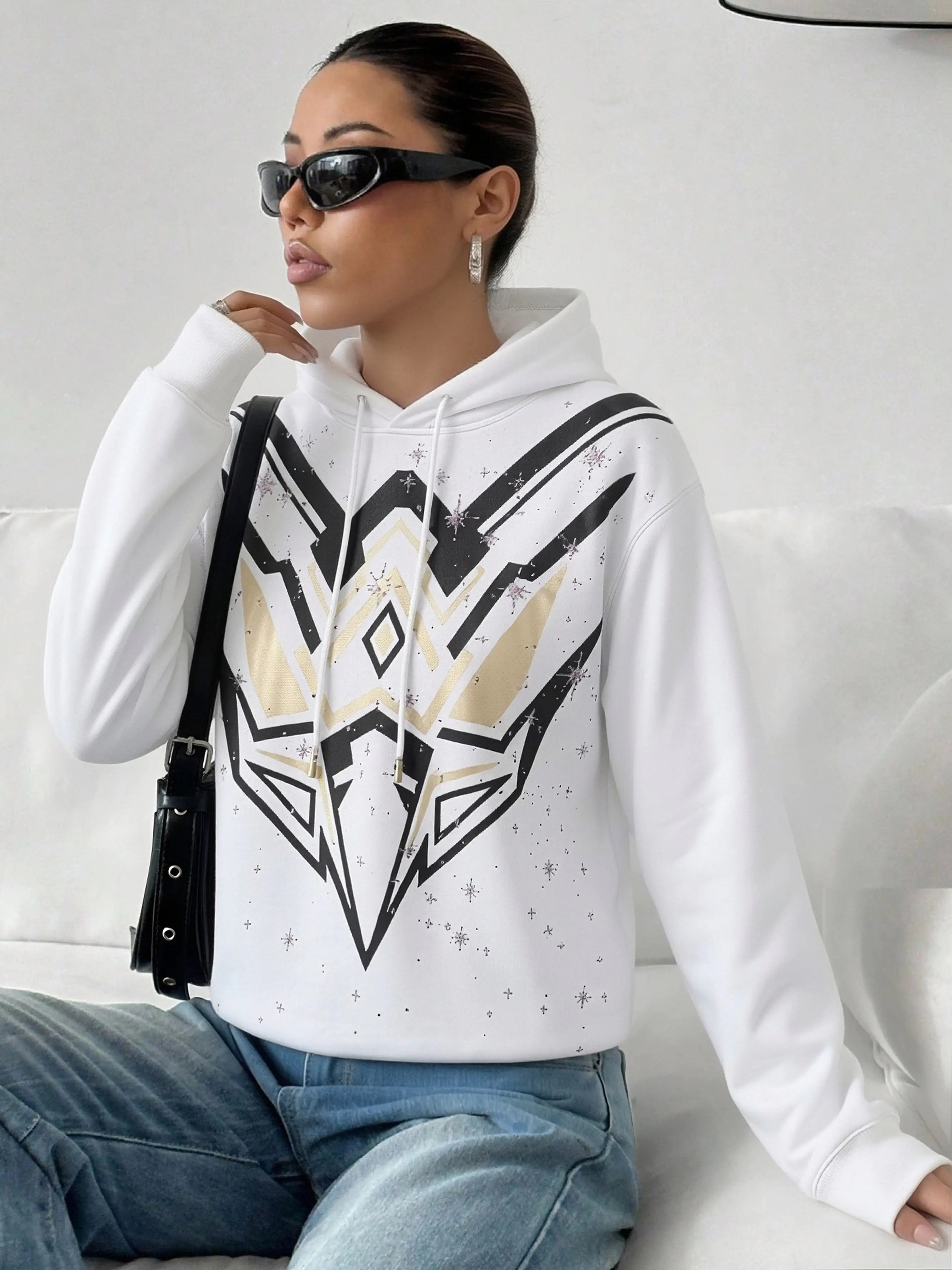 Woman wearing a white hoodie with a geometric design, sitting on a white couch. TCH Mech Graphic Rhinestone Crew Neck Sweatshirt