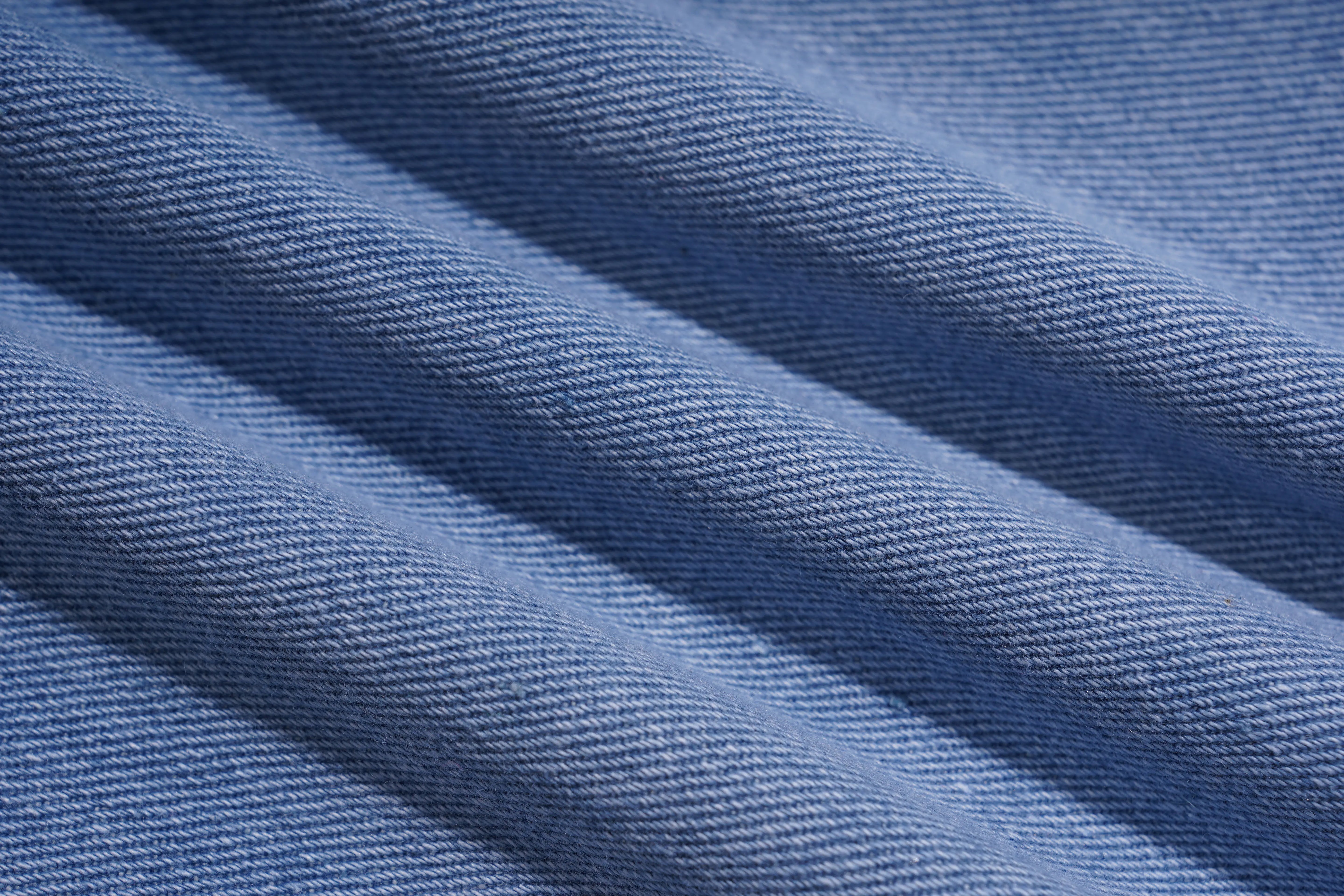 A close-up of blue denim fabric with a visible twill weave and soft diagonal folds. TCH Phoenix & Butterfly Rhinestone Wide Leg Jeans