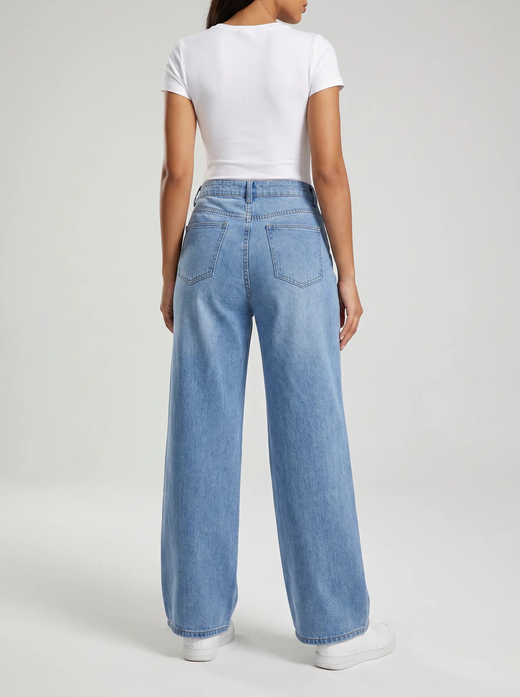 A model shown from the back wearing light-wash wide-leg denim jeans and a white short-sleeve crop top, standing against a light gray studio background. TCH Phoenix & Butterfly Rhinestone Wide Leg Jeans