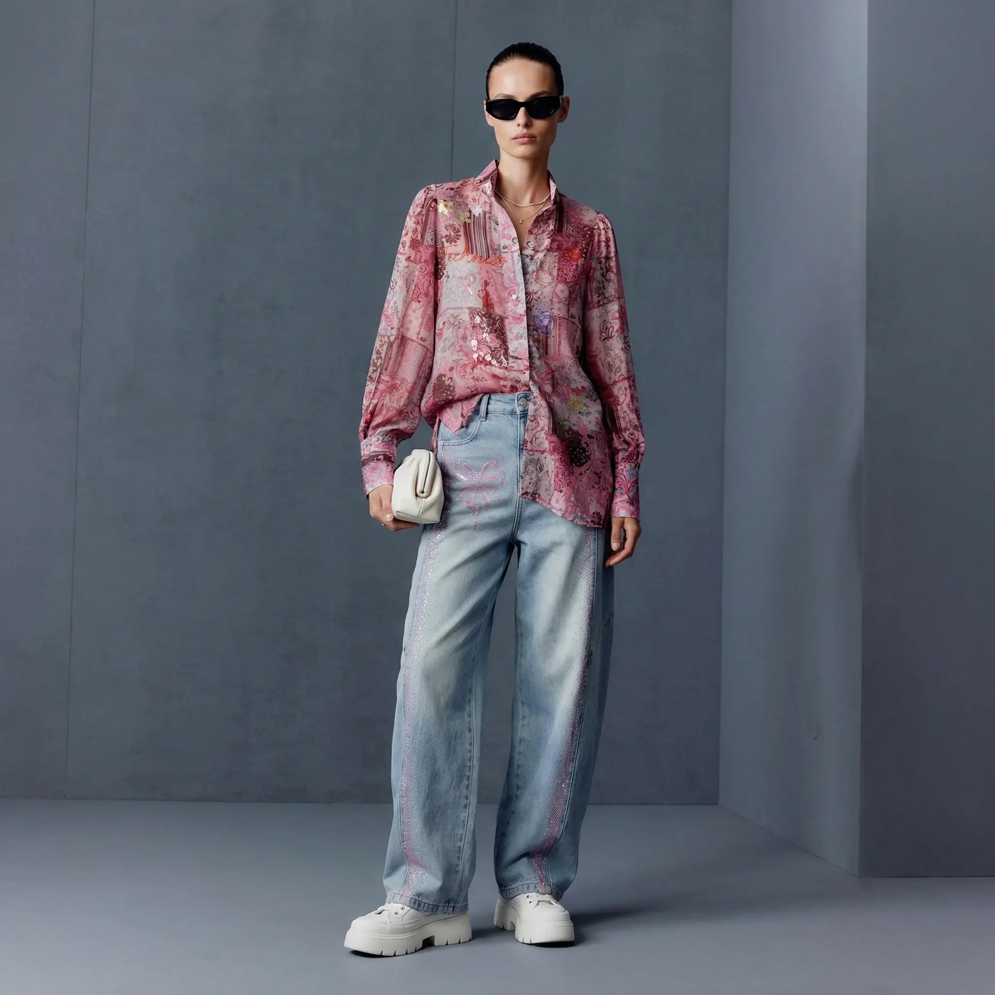 Person wearing a patterned shirt and light blue jeans against a gray background, TCH Pink Patchwork Rhinestone Floral Shirt