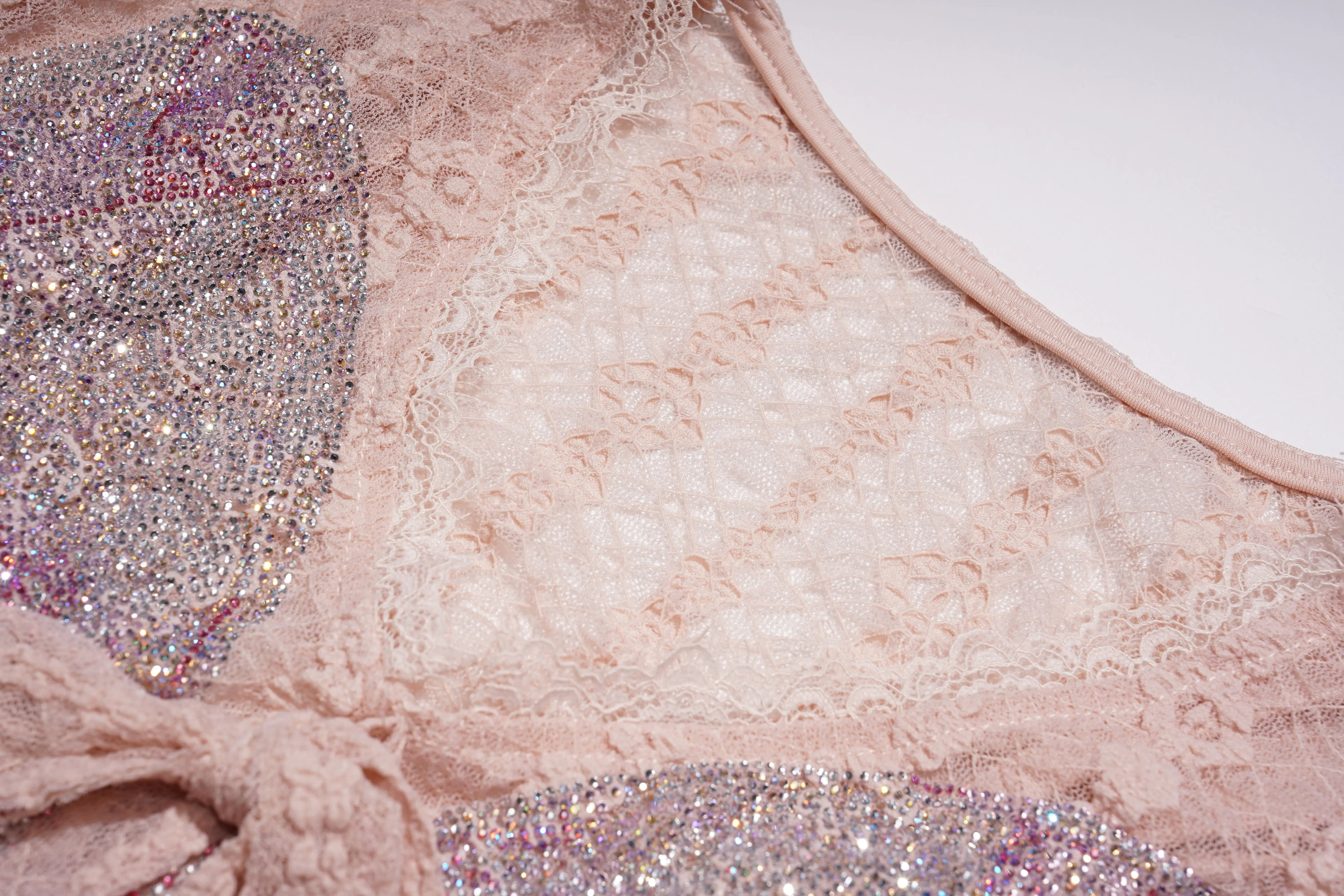Close-up of a pink lace garment with glittery accents on a white background, TCH Pink Rhinestone Bow Lace Layered Dress