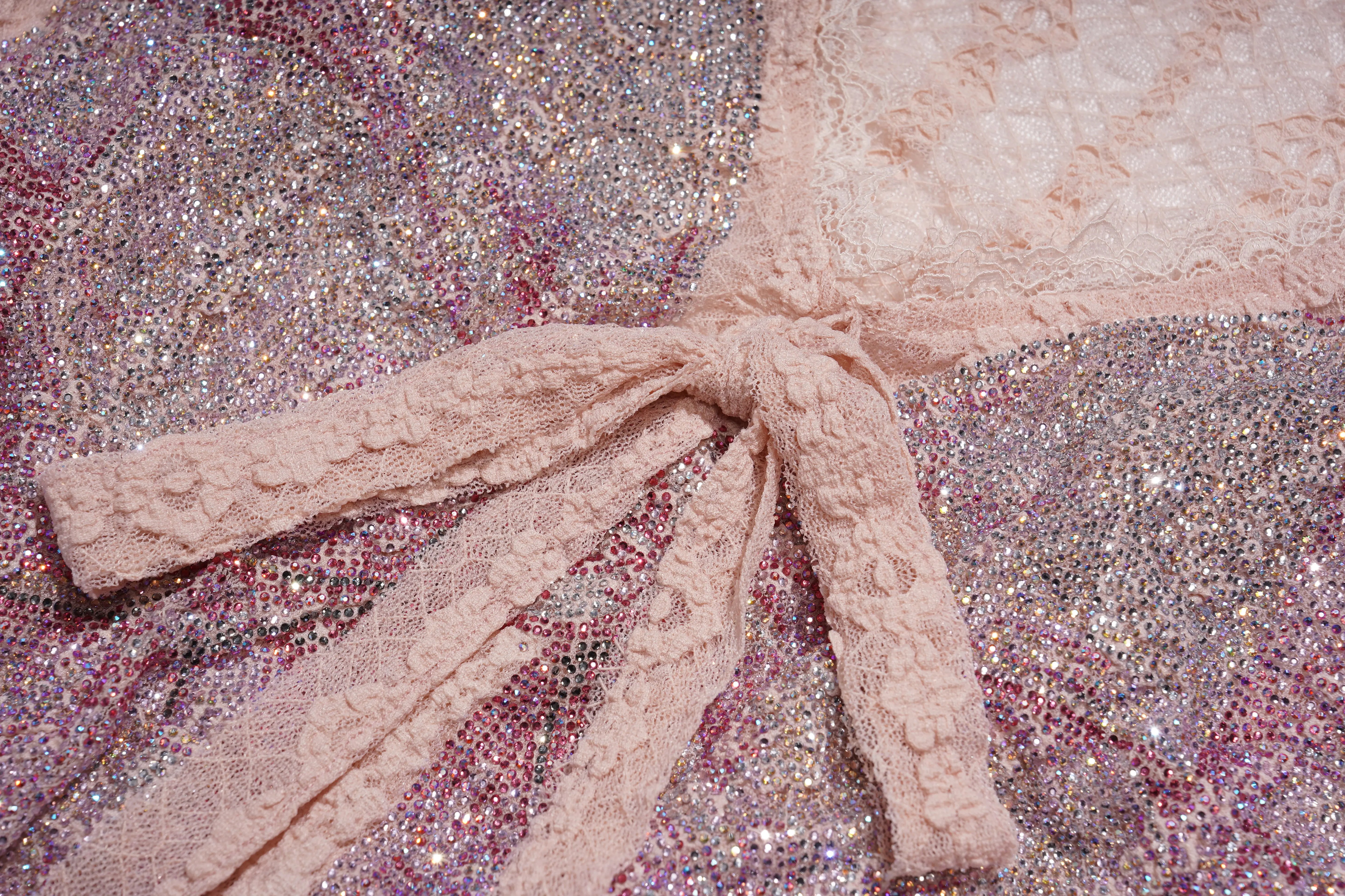 Close-up of a textured fabric with a bow on a glittery background, TCH Pink Rhinestone Bow Lace Layered Dress